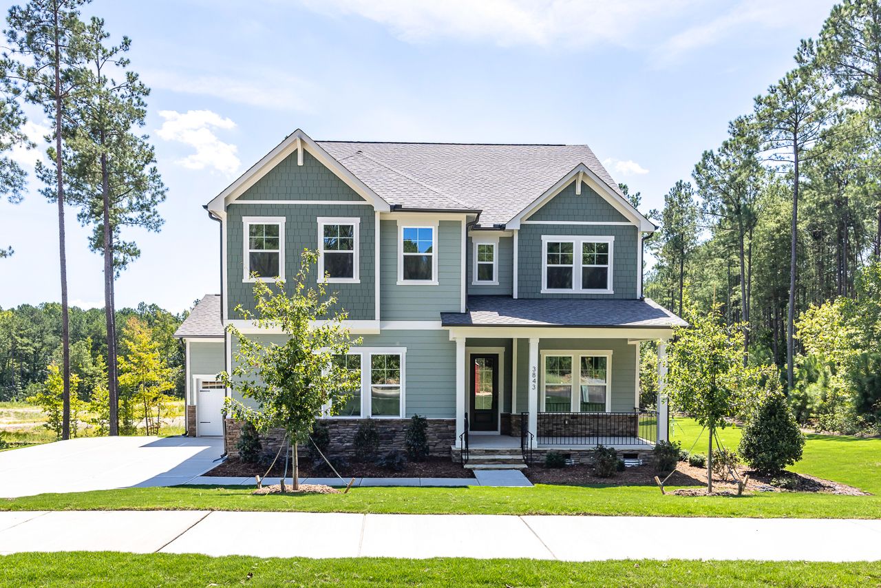 Two-story craftsman style home with sage green siding and covered front porch at Ashland community in Apex, NC by Davidson Homes