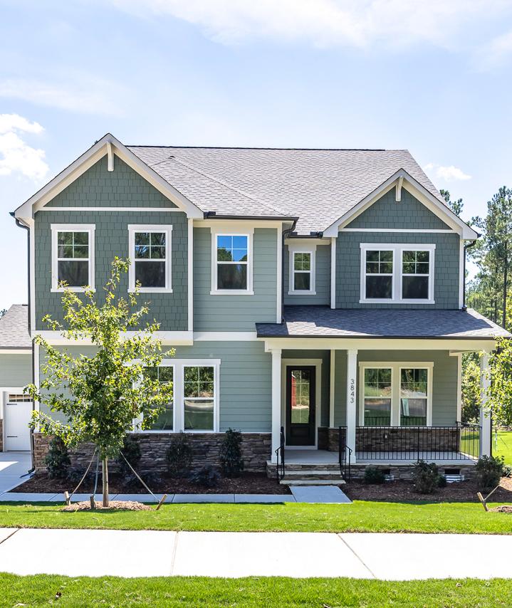 Two-story craftsman style home with sage green siding and covered front porch at Ashland community in Apex, NC by Davidson Homes