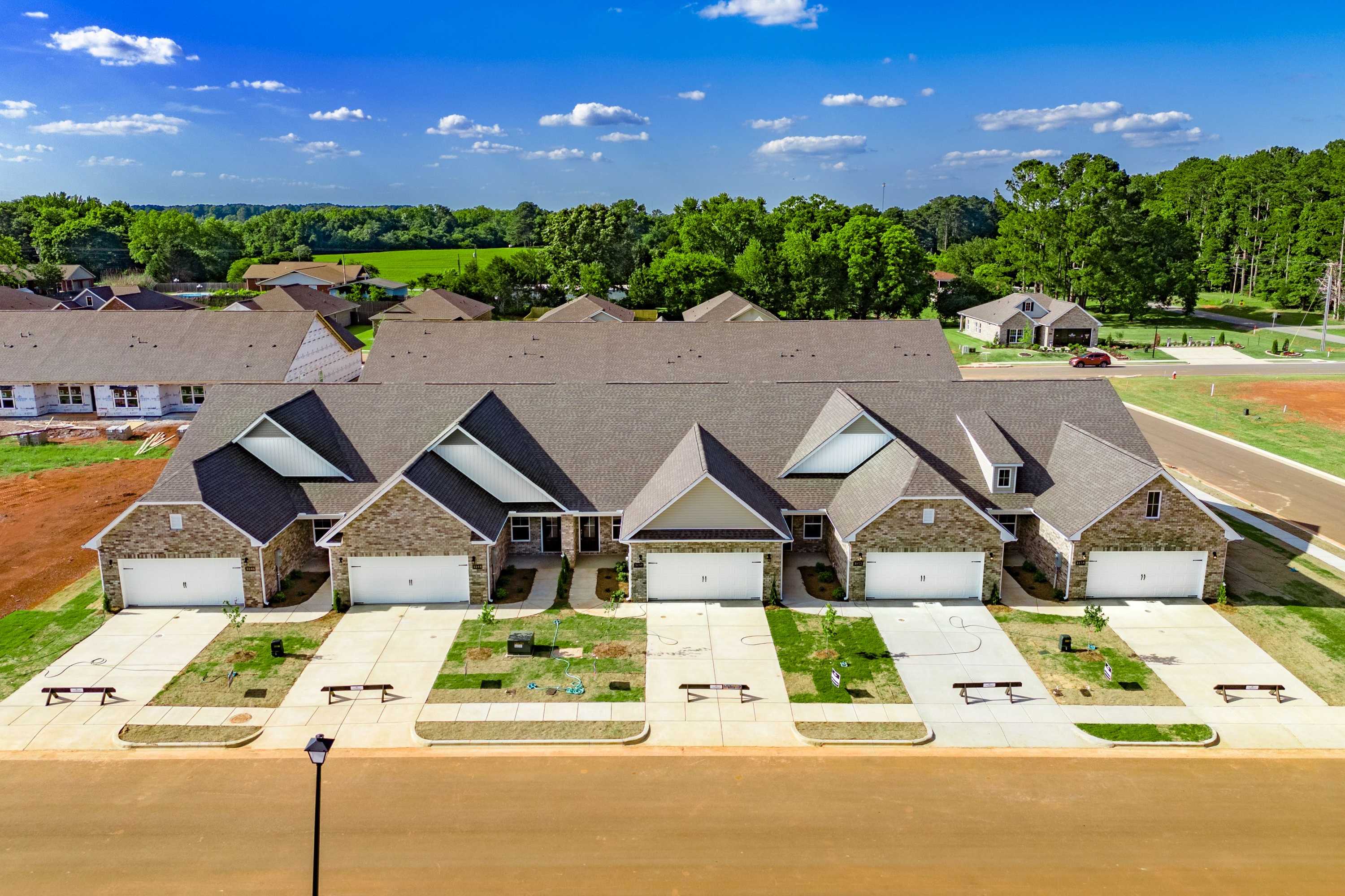 Row of modern townhomes at The Retreat at Hollon Meadow in Decatur AL with gabled roofs, garages, and concrete driveways