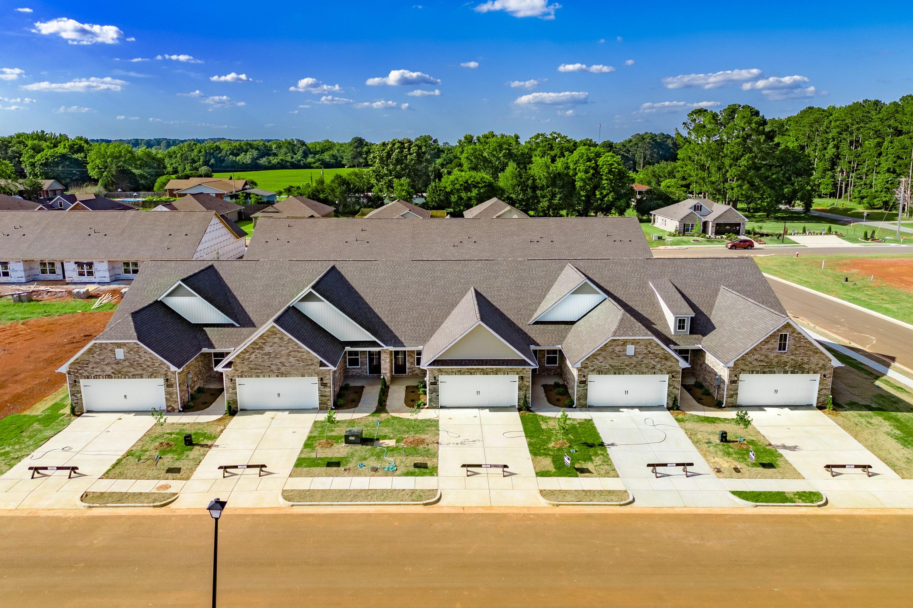 Row of modern townhomes at The Retreat at Hollon Meadow in Decatur AL with gabled roofs, garages, and concrete driveways