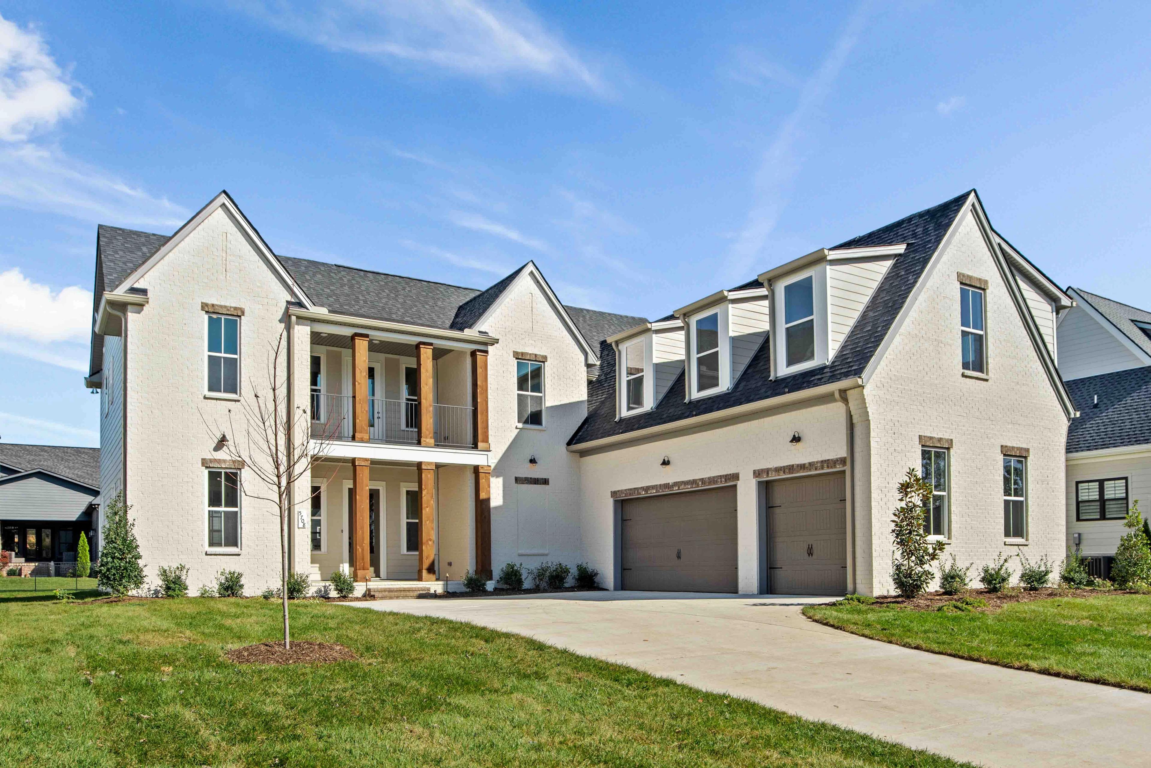 Modern white brick two-story home at Shelton Square in Murfreesboro TN with covered porch, balcony, and two-car garage