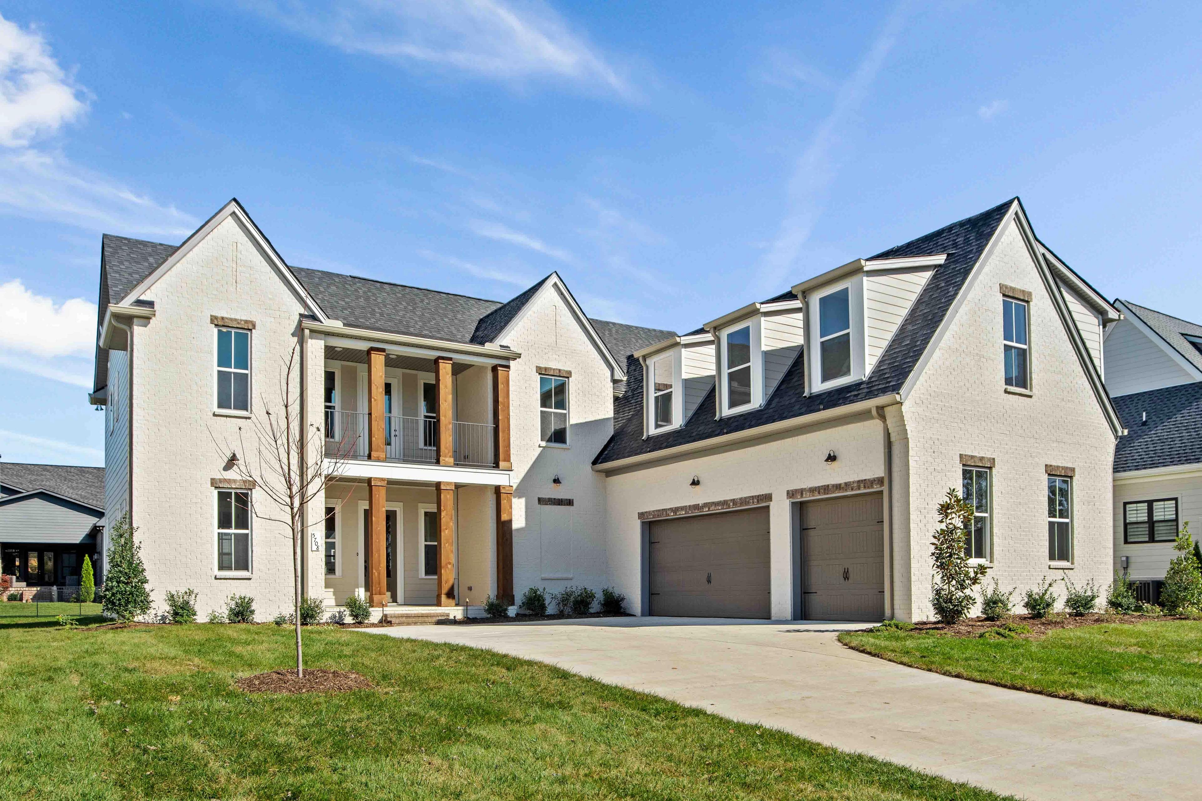 White brick Craftsman home exterior at Shelton Square in Murfreesboro TN with covered porch and two-car garage