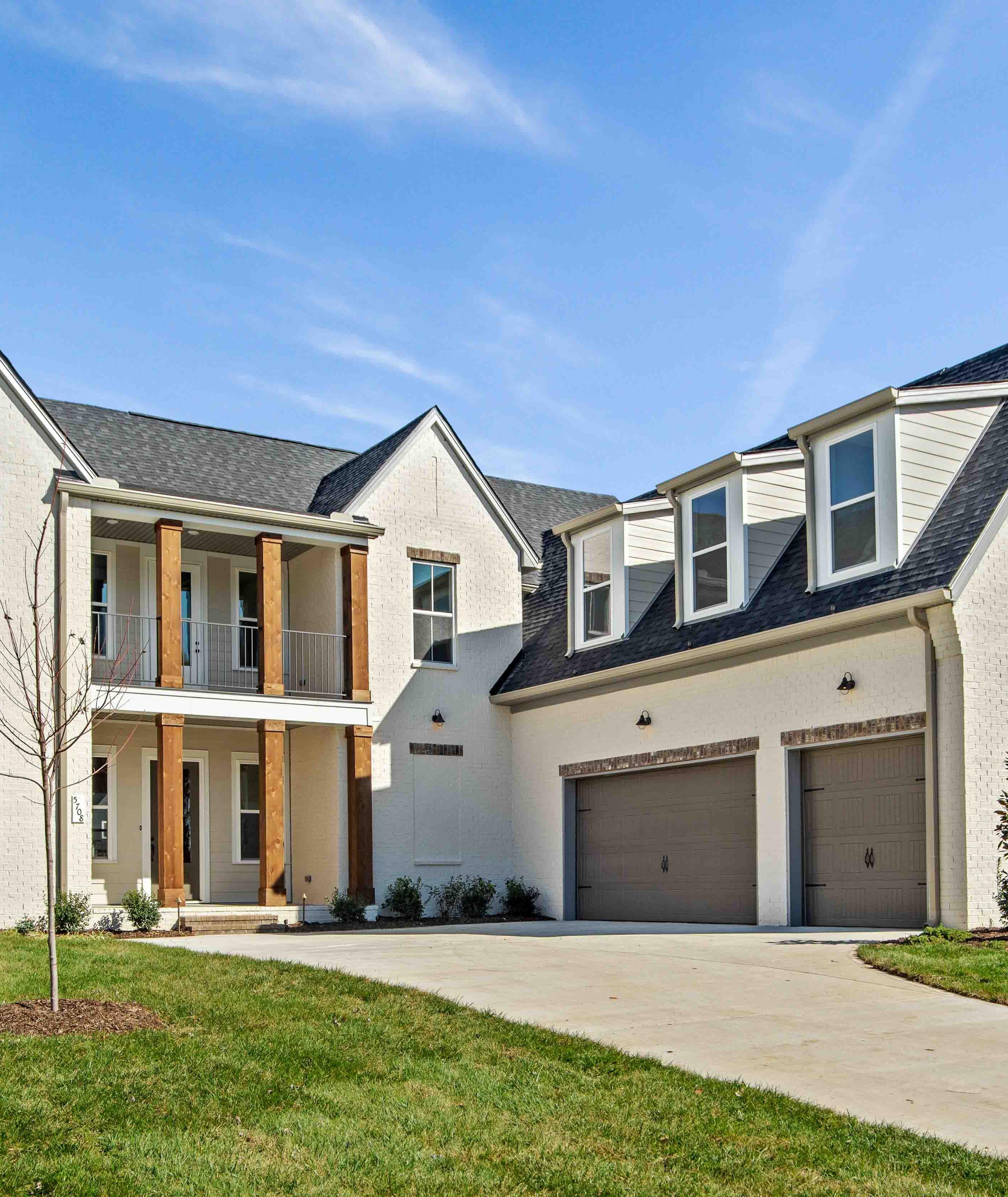 Modern white brick two-story home at Shelton Square in Murfreesboro TN with covered porch, balcony, and two-car garage