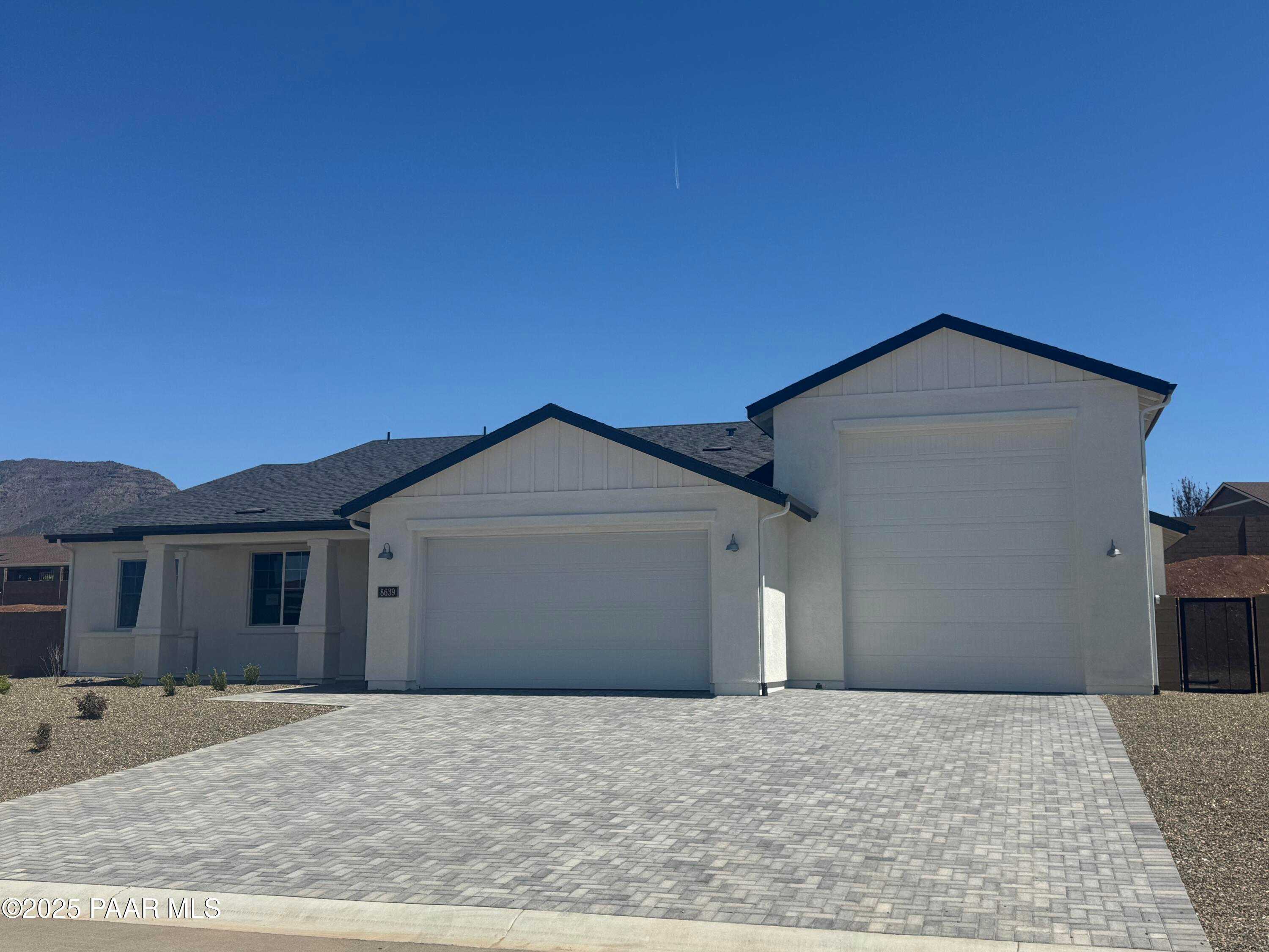 Modern 1-story white home with black trim, 2-car garage, paver driveway, and desert backdrop in Morningstar, Prescott Valley, Arizona
