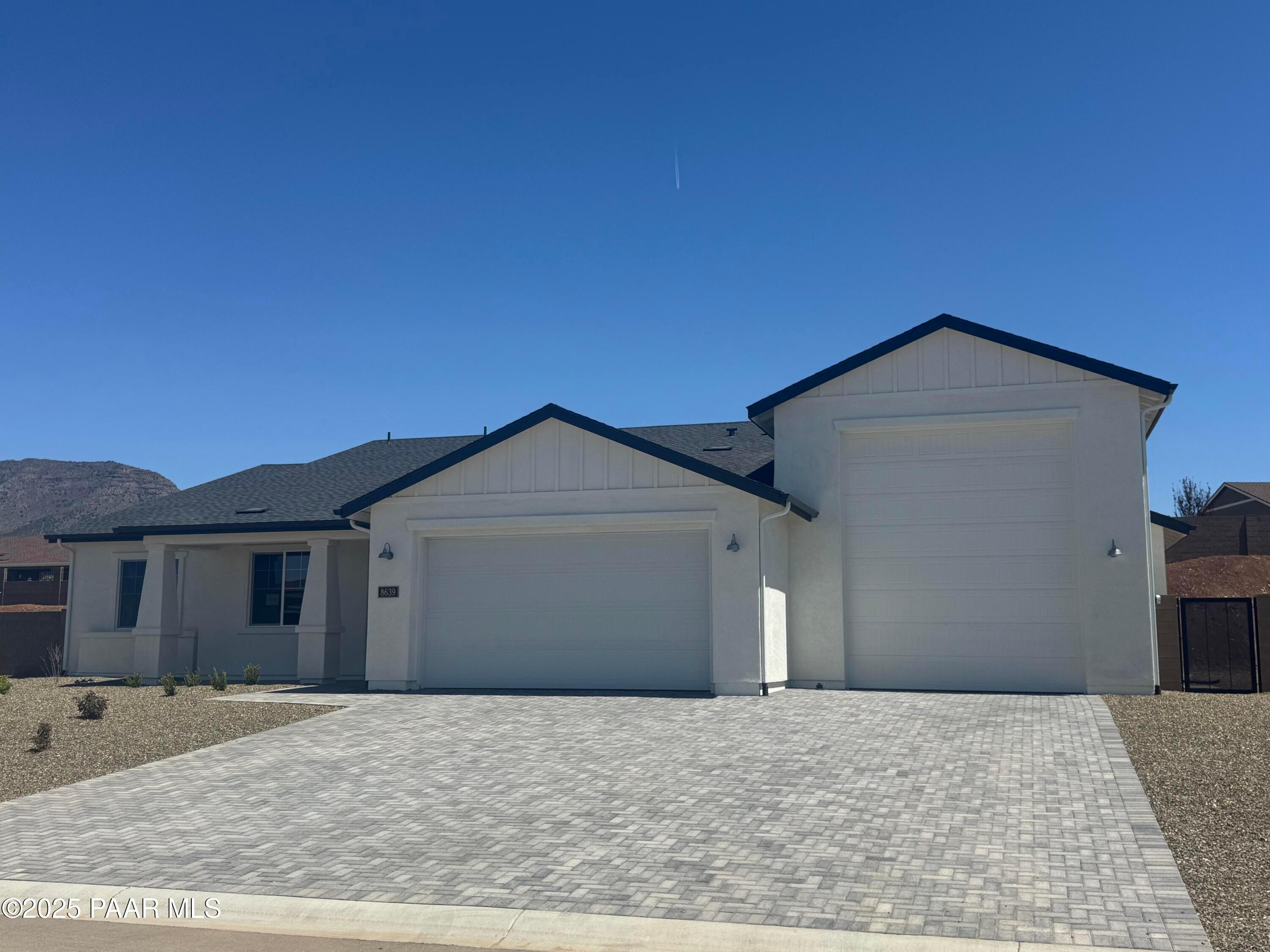 Modern 1-story white home with black trim, 2-car garage, paver driveway, and desert backdrop in Morningstar, Prescott Valley, Arizona