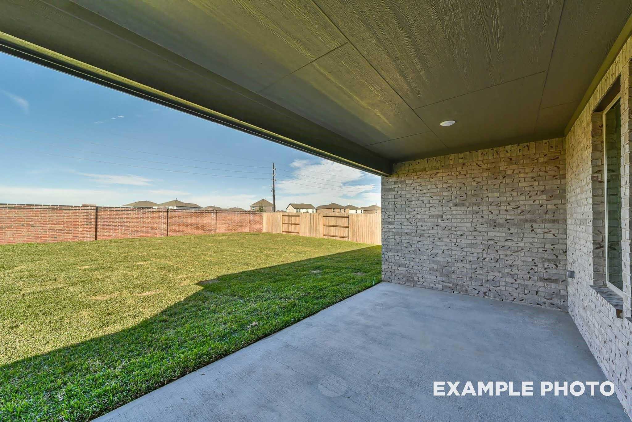 Covered back patio with concrete slab overlooking fenced grassy backyard in Davidson Homes The Philip C, Rosharon, Texas