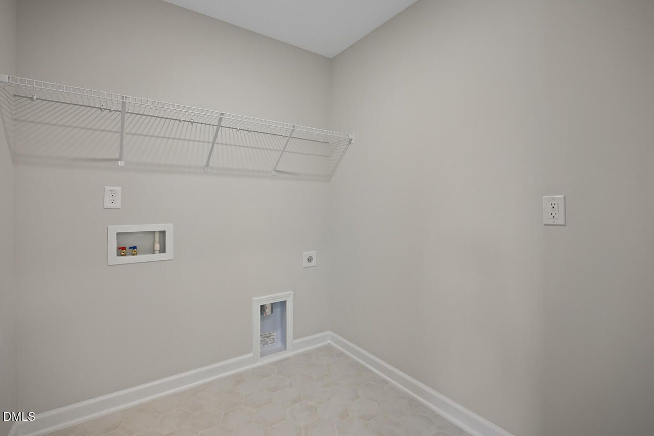 Laundry room with white wire shelving and washer-dryer hookups in The Chestnut floor plan at Wendell Ridge, North Carolina.