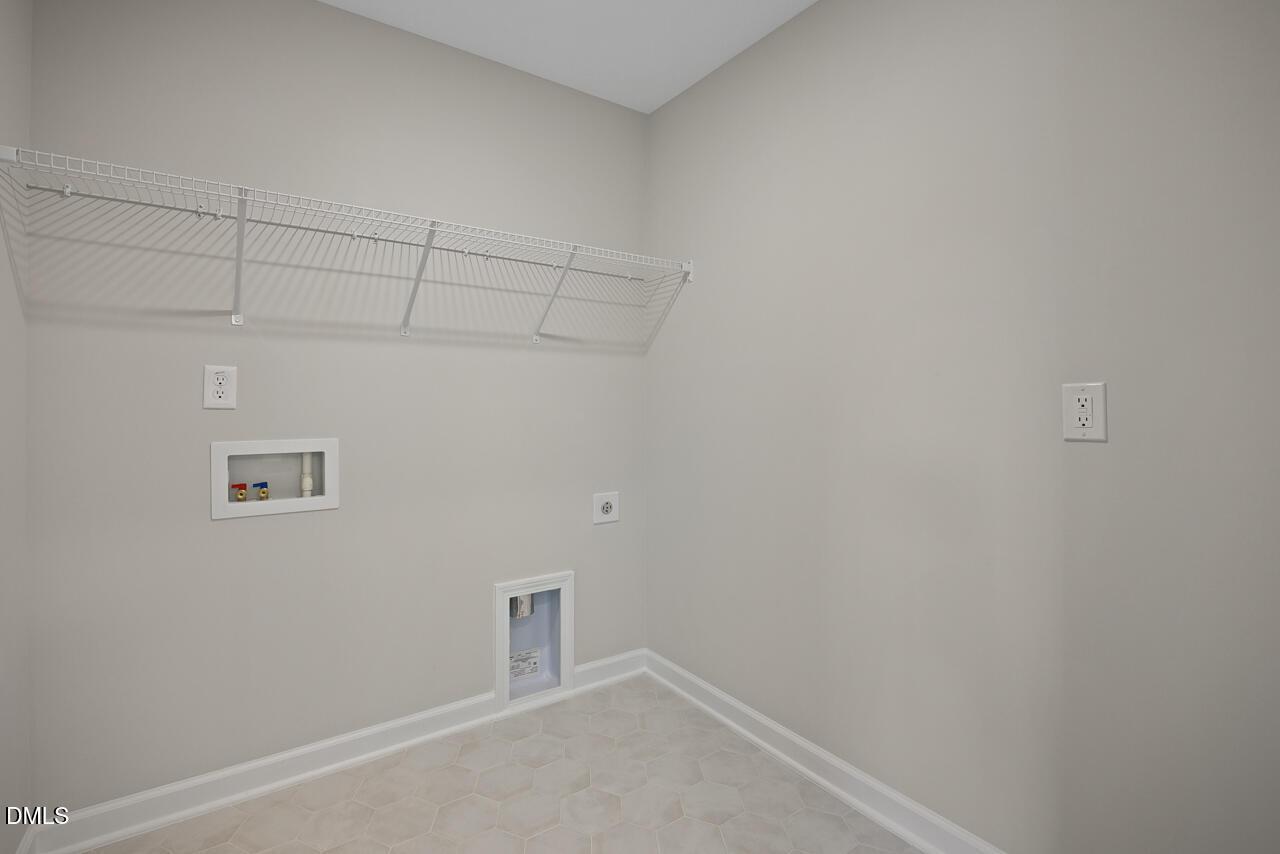 Laundry room with white wire shelving and washer-dryer hookups in The Chestnut floor plan at Wendell Ridge, North Carolina.