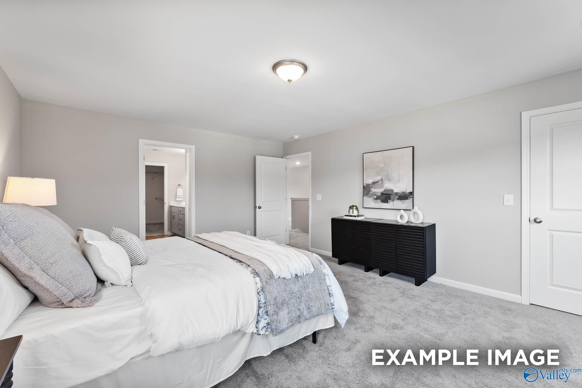 Serene master bedroom with king bed, gray bedding, black dresser, and en-suite bath in Davidson Homes The Charm, Huntsville, AL