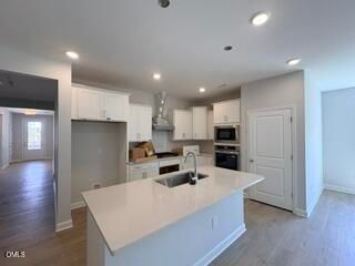 Modern kitchen with white cabinets and quartz island in The Daphne D floor plan at Woodland Crossing, Zebulon, North Carolina.