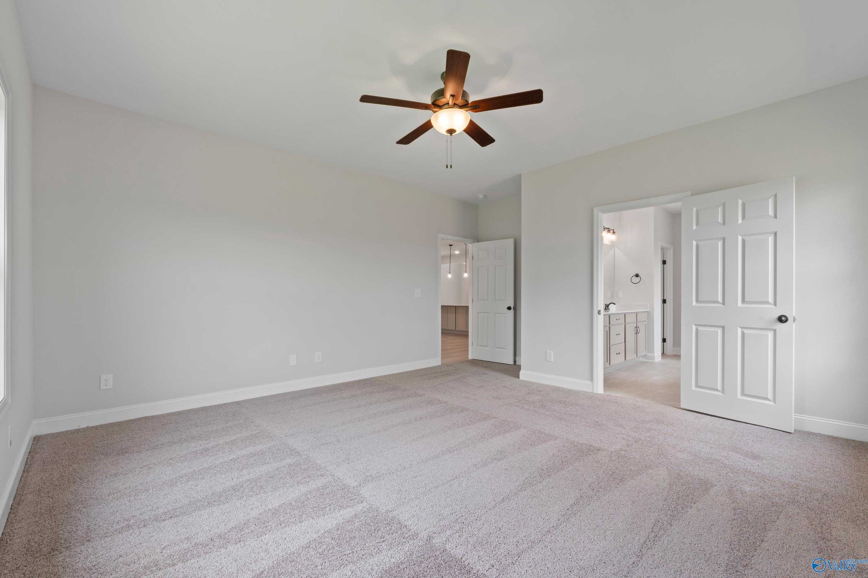 Spacious master bedroom with ceiling fan, beige carpet, and en-suite bath in Davidson Homes The Kirkland with Bonus, Harvest, AL