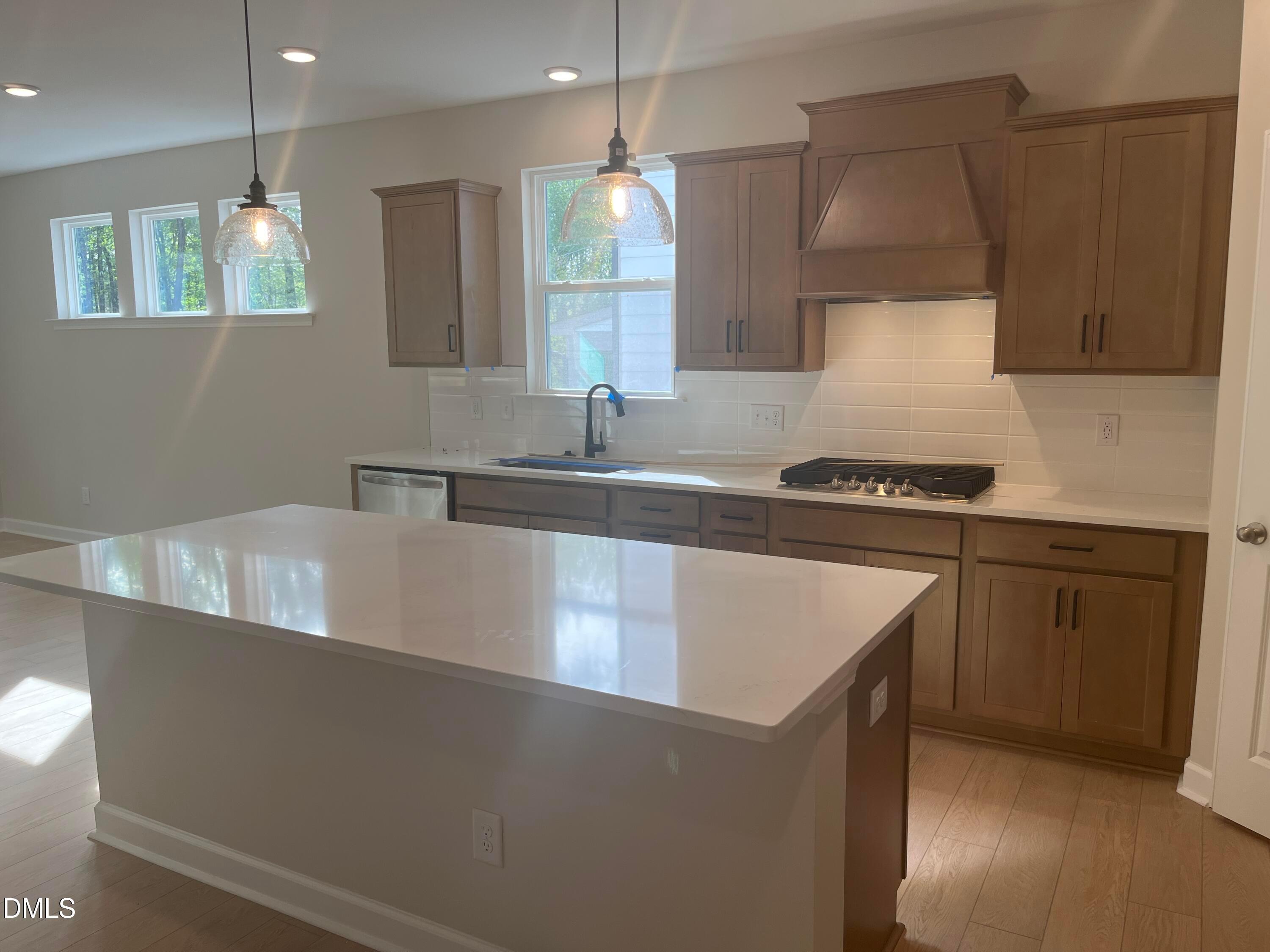Modern kitchen with quartz island, shaker cabinets, gas range, and pendant lights in Davidson Homes Ashport L, Wake Forest, NC