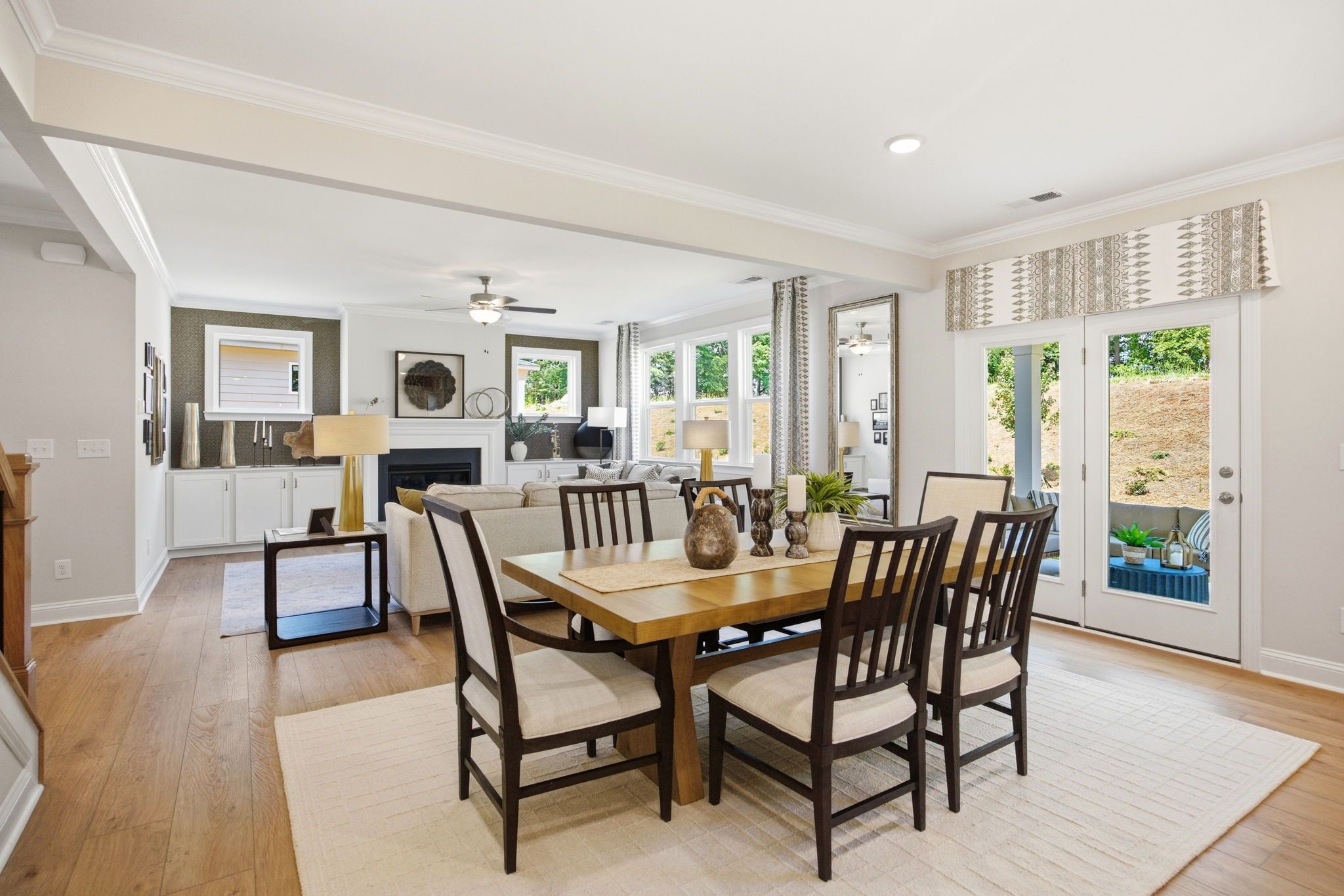 Open-concept dining and living room at Enclave at Belmont in Belmont NC with hardwood floors, wooden table, fireplace, and sliding doors