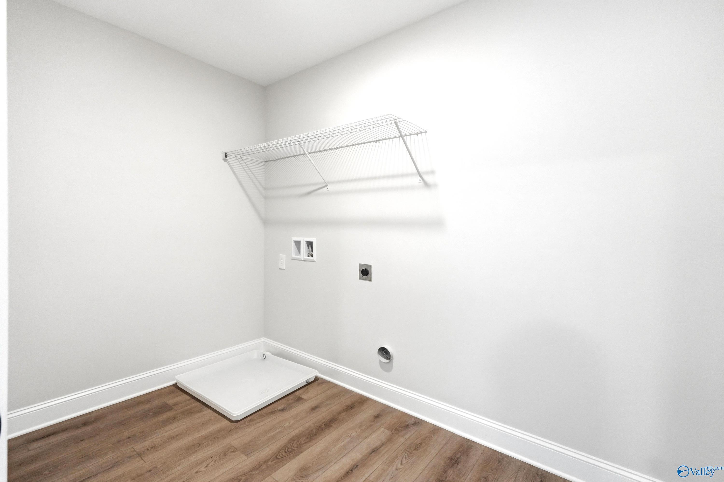 Laundry room with utility connections, white wire shelving, and floor pan in The Shelby A home by Davidson in Clearview.