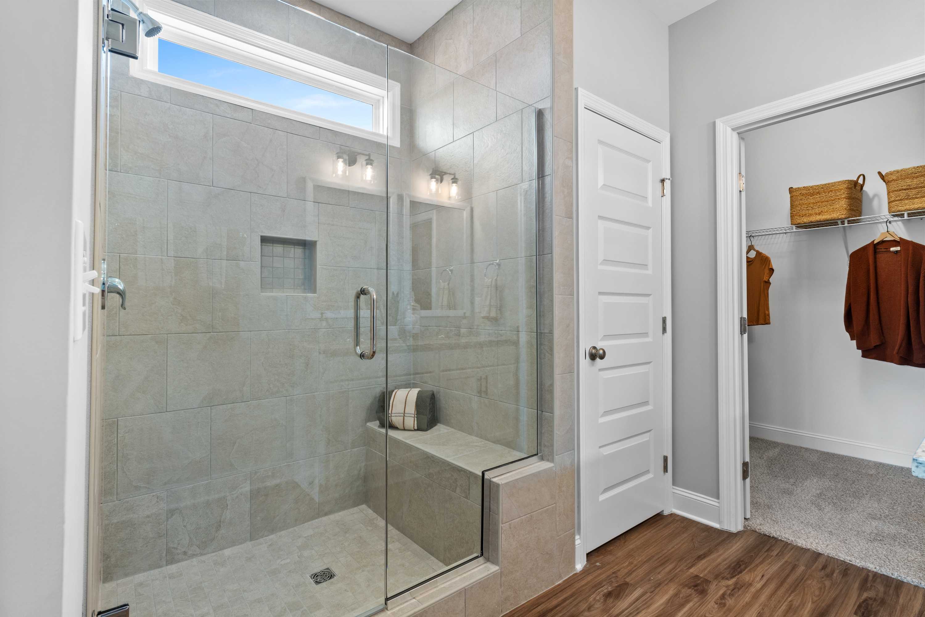 Frameless glass shower in master bath at Wood Trail Toney Alabama with subway tile bench skylight and walk-in closet