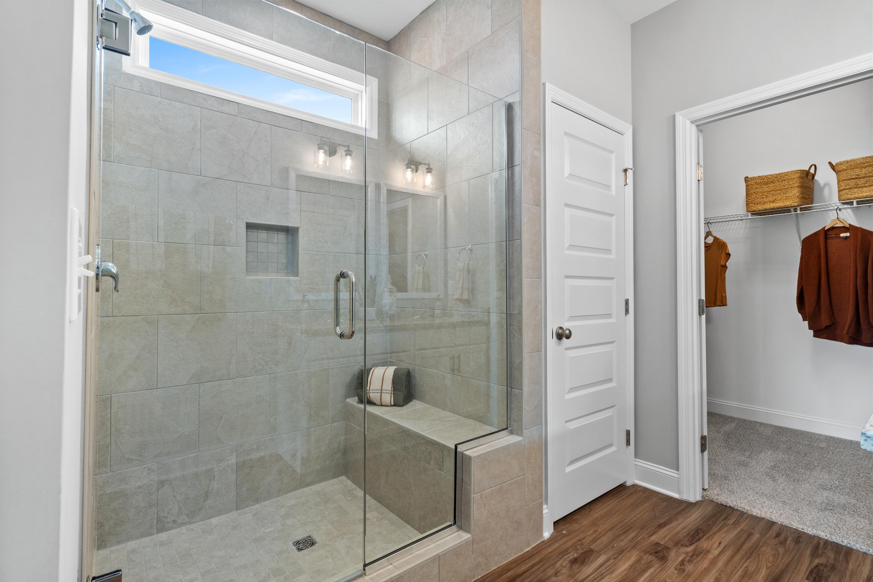 Frameless glass shower in master bath at Wood Trail Toney Alabama with subway tile bench skylight and walk-in closet