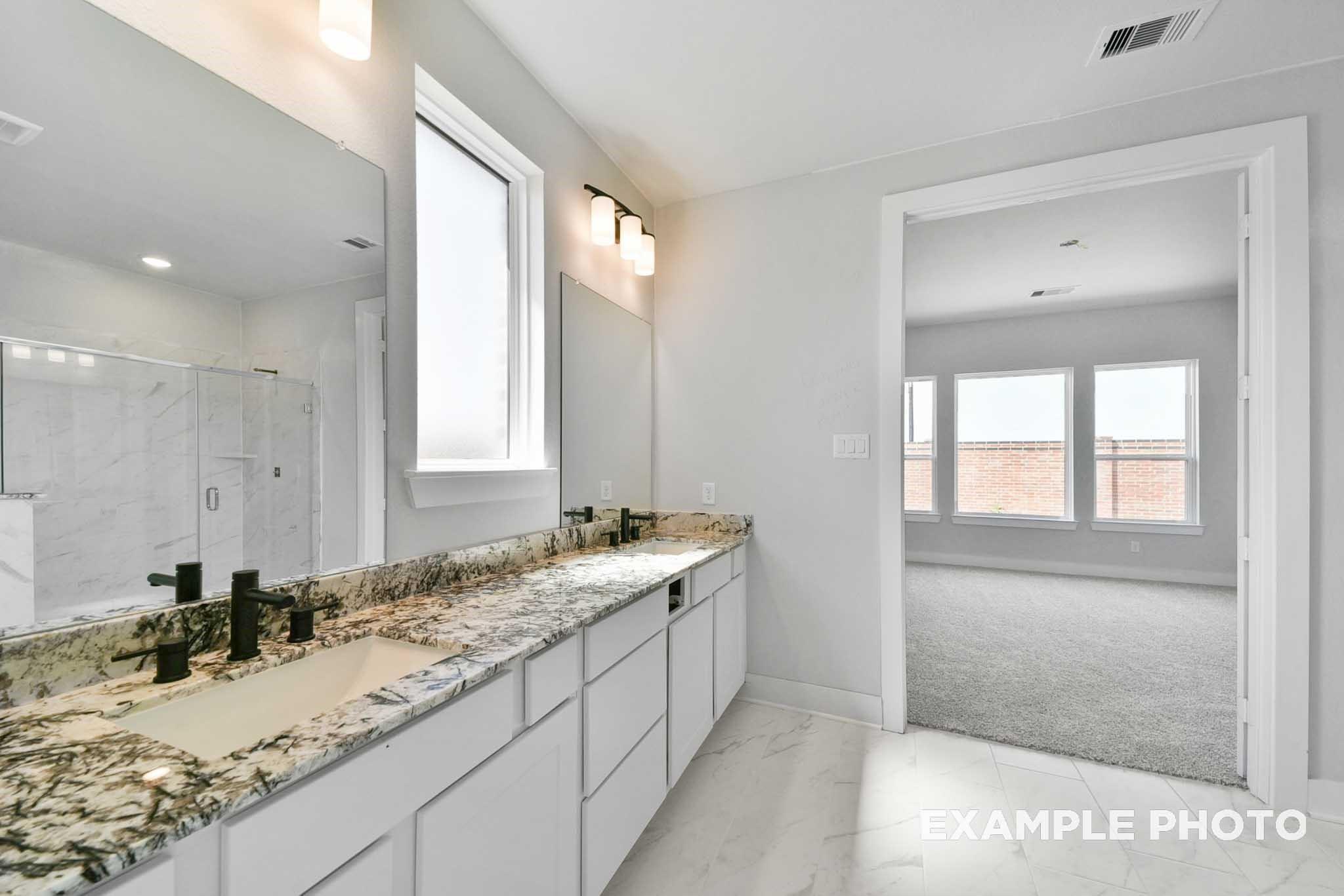 Elegant master bathroom with double granite vanity, glass shower, and bedroom view in Davidson Homes The George A, Lago Mar, Texas City