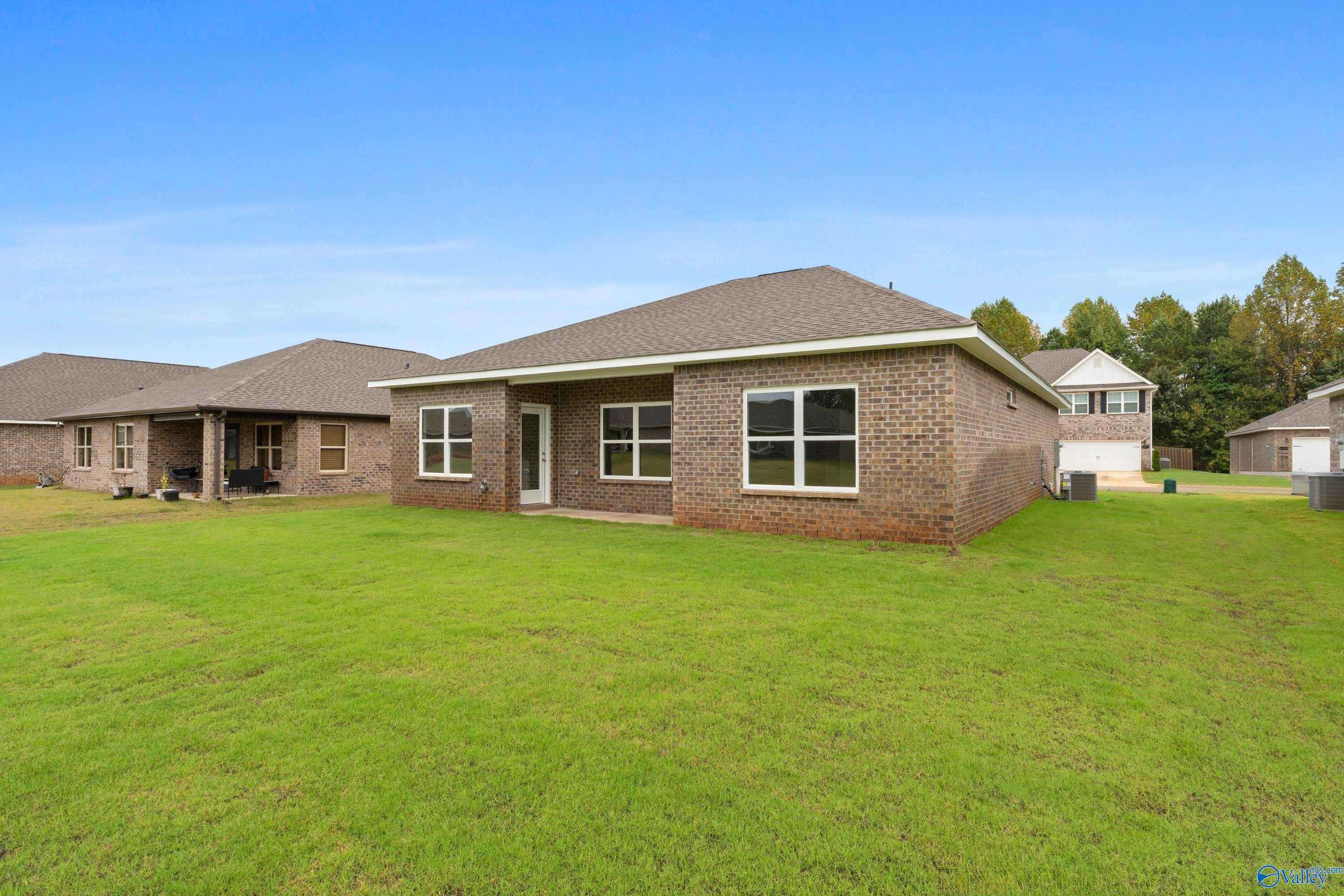Single-story brick home with covered porch, 2-car garage, and lush green yard in Ricketts Farm, Athens, Alabama