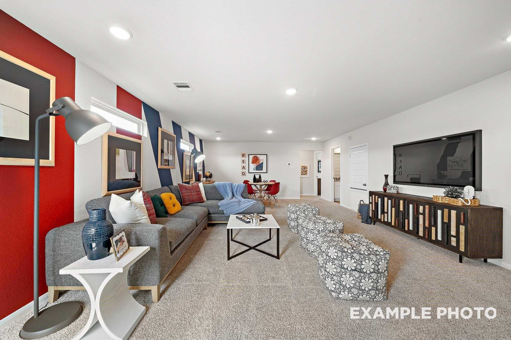 Cozy game room featuring red accent wall, gray L-shaped sofa, mounted TV in Davidson Homes San Marcos E, Conroe Texas