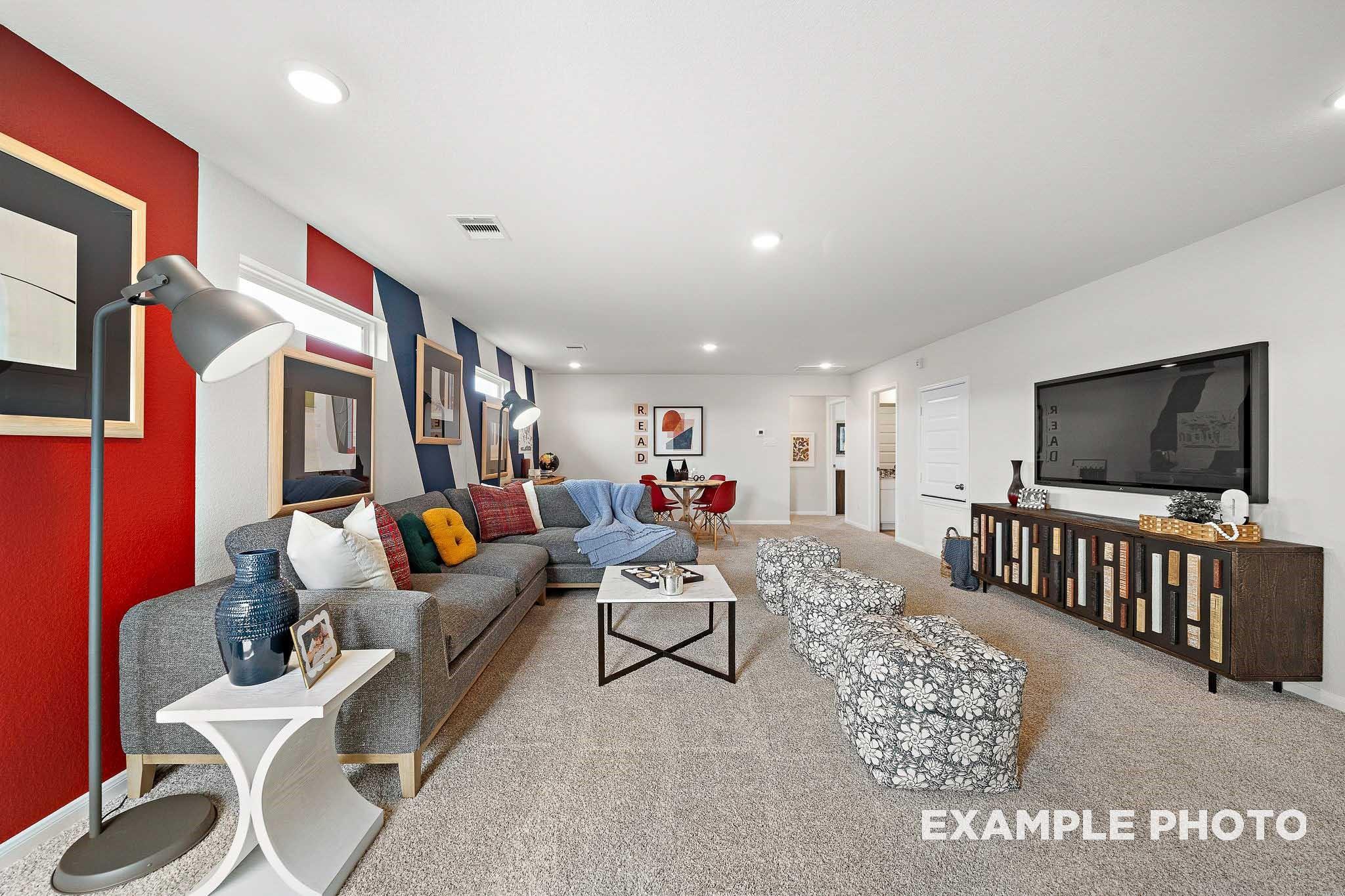 Cozy game room featuring red accent wall, gray L-shaped sofa, mounted TV in Davidson Homes San Marcos E, Conroe Texas