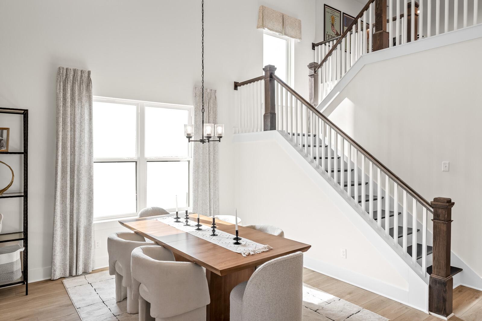 Open-concept living dining room at Benders Cove in Mt. Juliet TN featuring hardwood floors, neutral sofa, wood table and sheer curtains