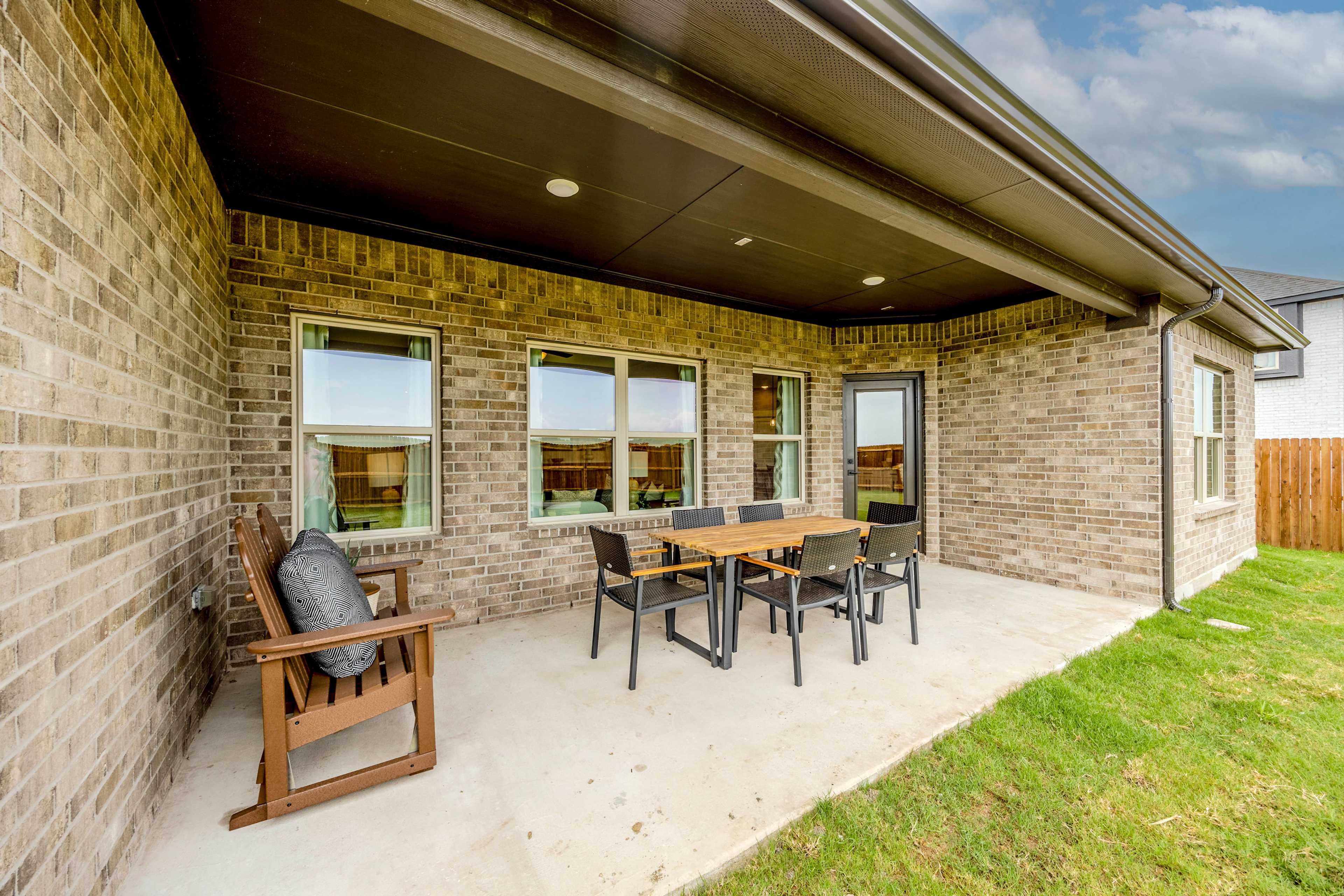 Covered patio with outdoor dining set at Waverly Estates in Josephine Texas featuring brick walls, large windows, and grassy yard