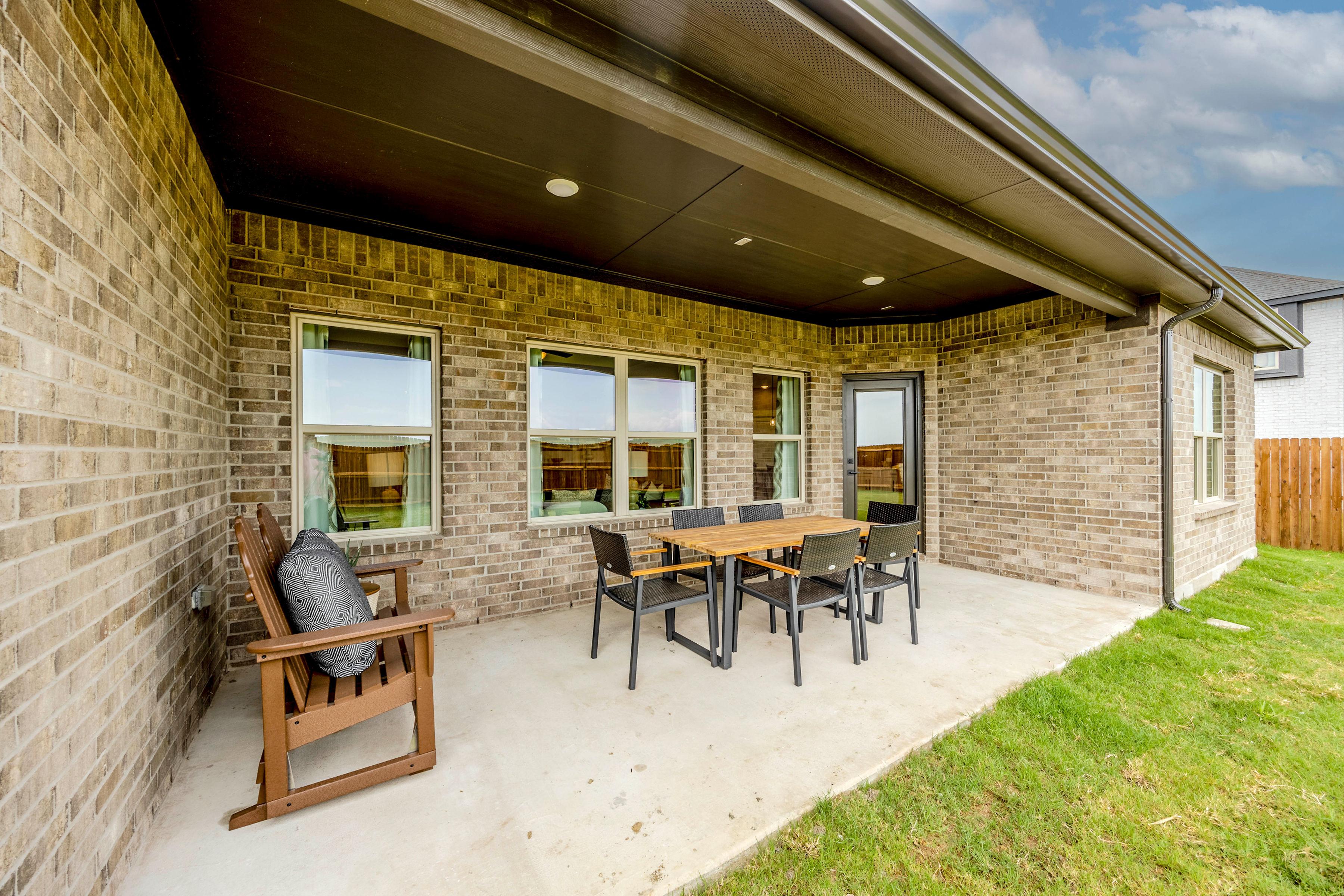 Covered patio with outdoor dining set at Waverly Estates in Josephine Texas featuring brick walls, large windows, and grassy yard