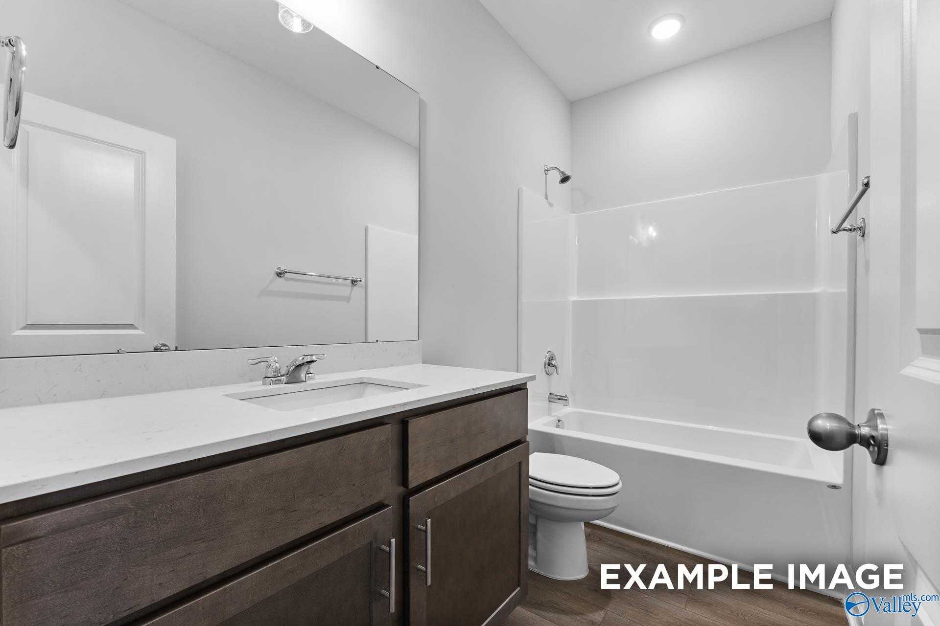 Modern bathroom with double vanity, soaking tub-shower combo, and dark wood cabinets in Davidson Homes The Daphne C, Arab, Alabama