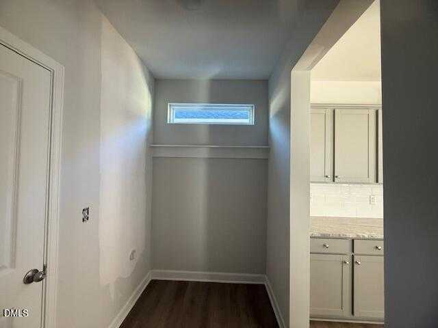 Bright hallway with coat closet, high transom window, and adjacent white kitchen cabinets in The Gavin B home, Lillington, NC