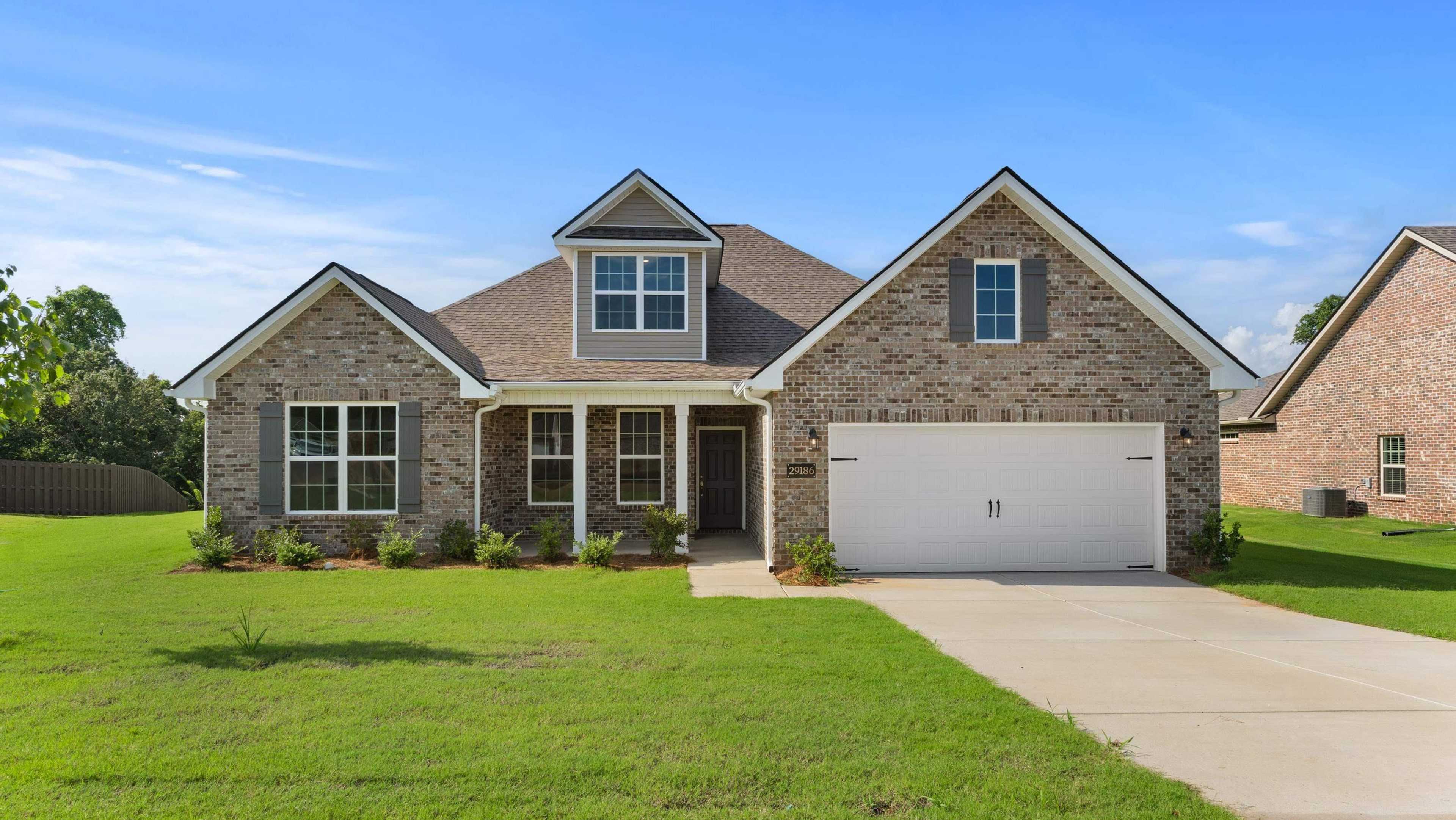 Modern brick ranch home with gabled roof, double garage, and lush green lawn at Davidson Homes open house, 29186 Canoe Circle