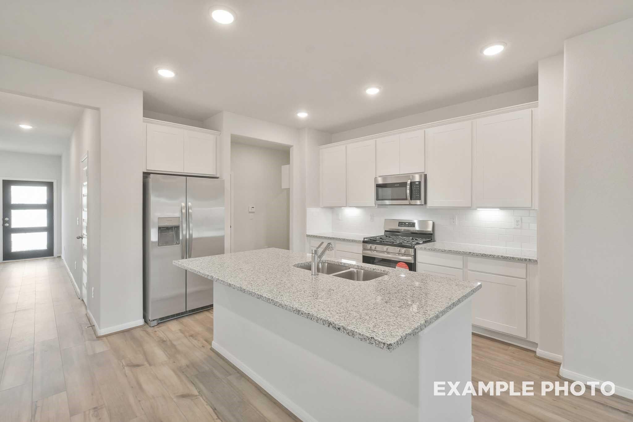 Modern kitchen with granite island, white shaker cabinets, and stainless appliances in Davidson Homes Brazos E plan, Conroe, TX
