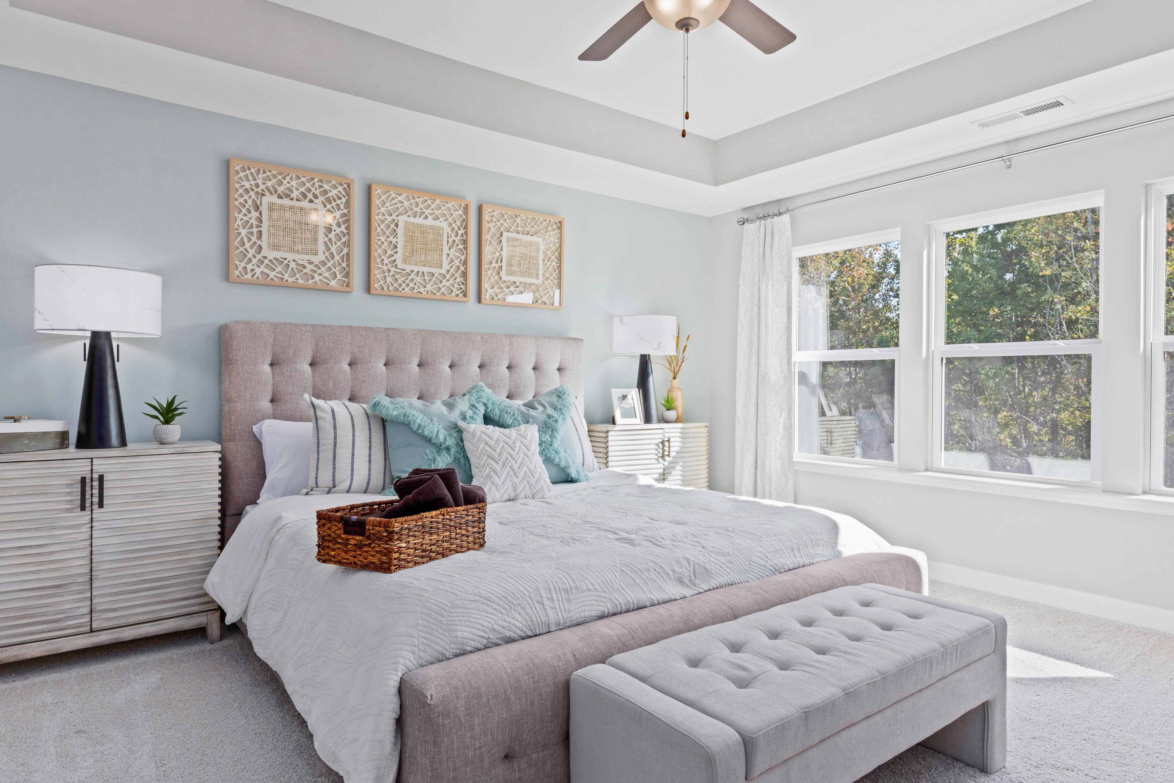Serene primary bedroom at Enclave at Belmont in Belmont NC with tufted bed, teal pillows, and large windows