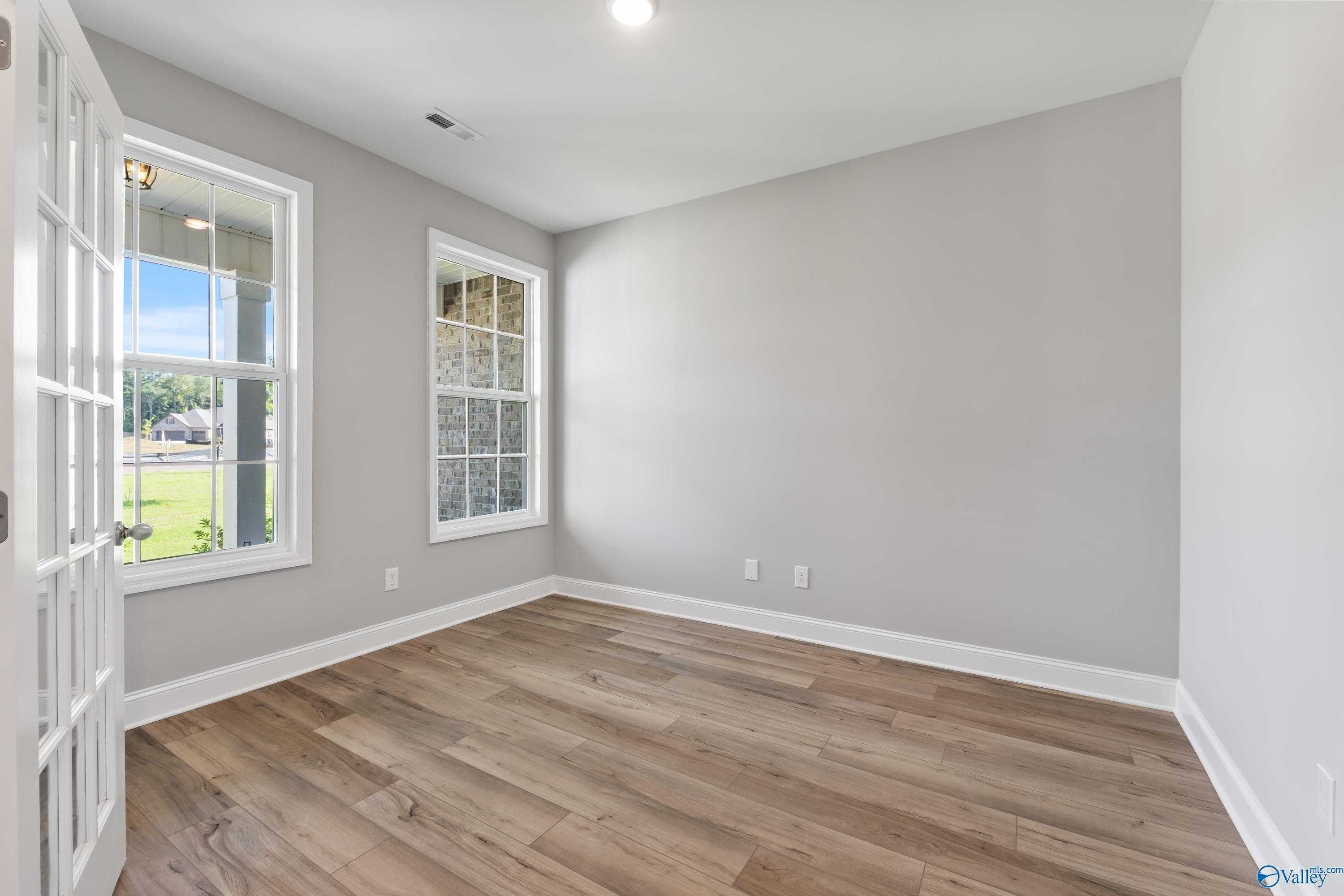 Bright bedroom with light gray walls, large windows, French doors, hardwood floors in Davidson Homes The Rockford, Harvest, AL