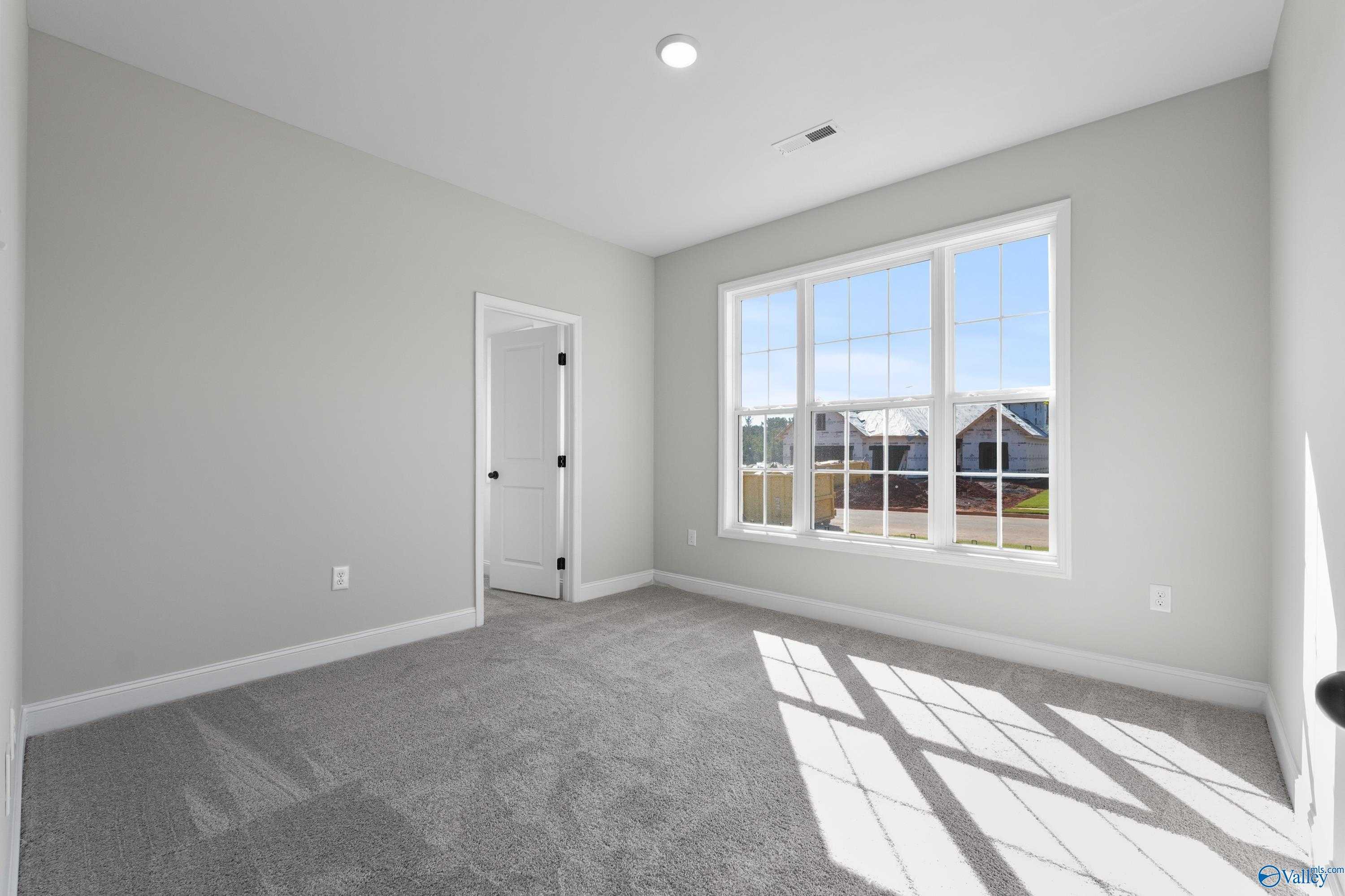 Bright bedroom with large windows, gray walls, and carpet in Davidson Homes Montgomery C, Decatur, Alabama