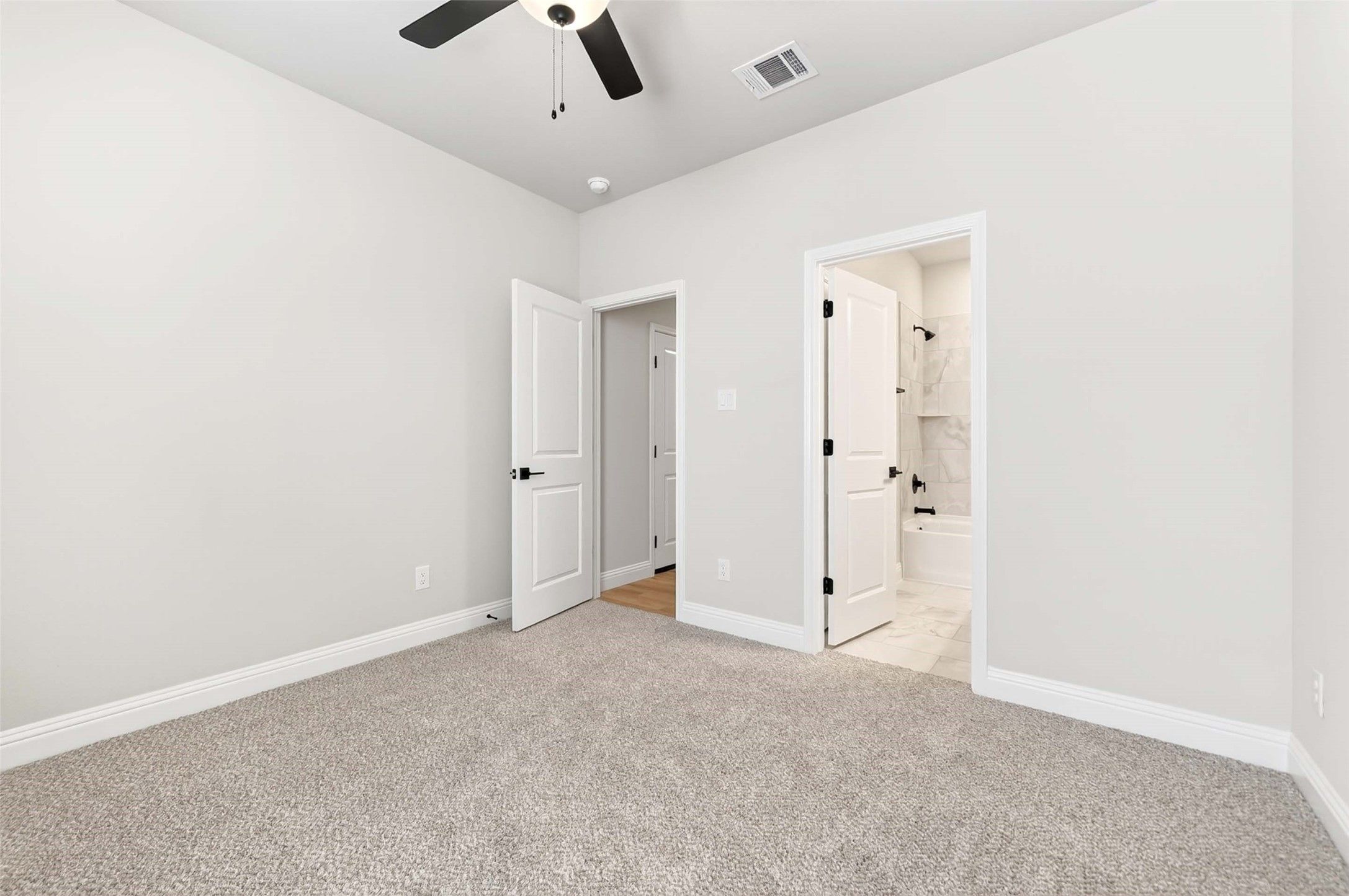 Secondary bedroom with plush carpet and en-suite bath in The Holly C floor plan by Davidson Homes in Anna, Texas.