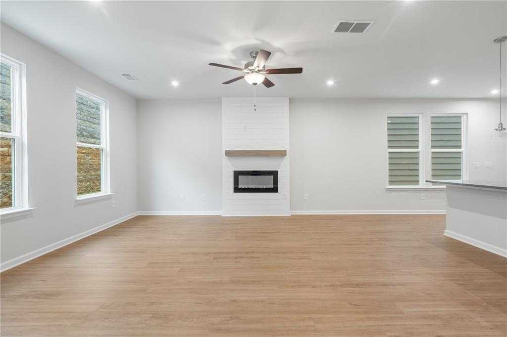 Spacious open living room with modern gas fireplace, hardwood floors, and large windows in Davidson Homes The Cary A, Kennesaw, GA