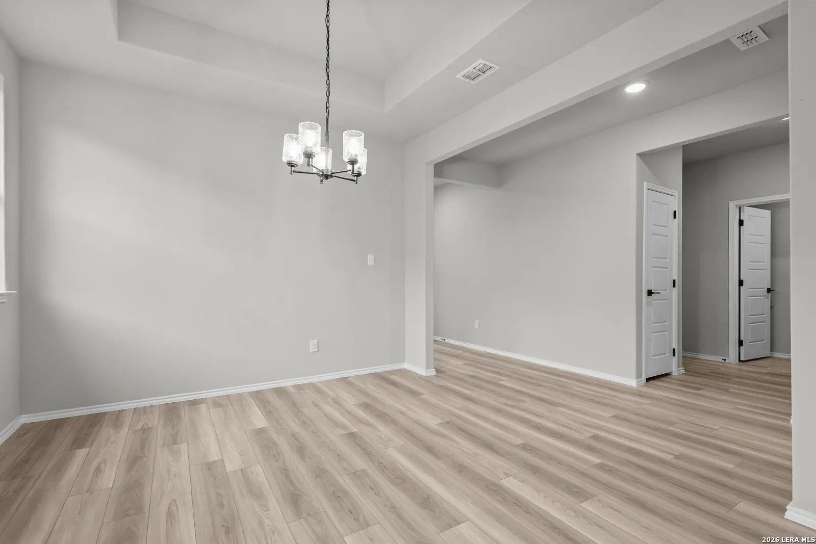 Elegant dining area with tray ceiling and chandelier in The Glenwood E floor plan at Comanche Ridge, San Antonio, Texas.