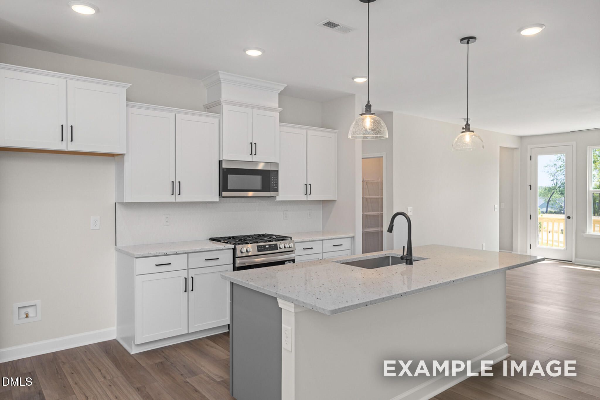 Modern kitchen with white cabinets and island in The Mitchell floor plan at Camden Park, Knightdale, North Carolina.
