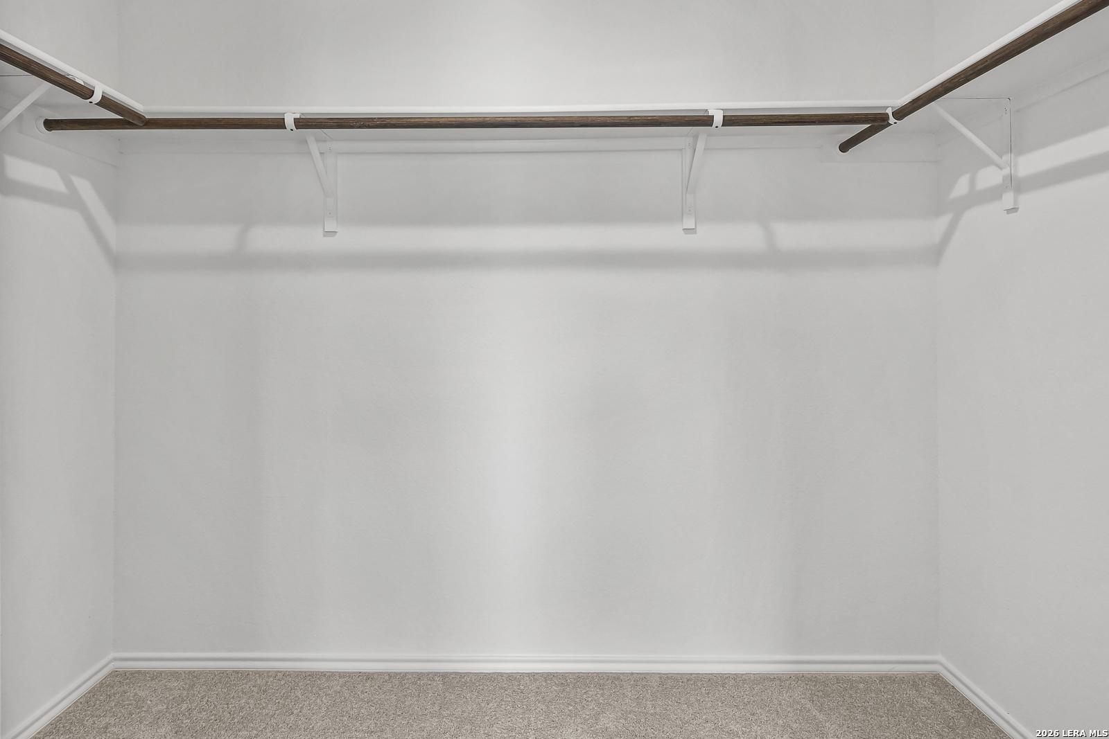 Spacious walk-in closet with hanging rods in The Gillian C floor plan by Davidson Homes in Meadows at Oak Creek, San Antonio.