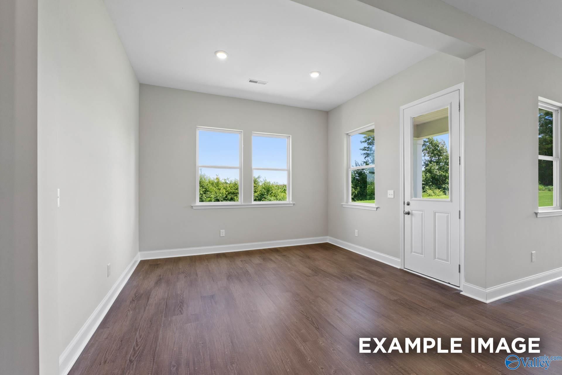Bright flex room with large windows, white walls, hardwood floors in Evermore Homes The Arcadia, Owens Cross Roads, Alabama