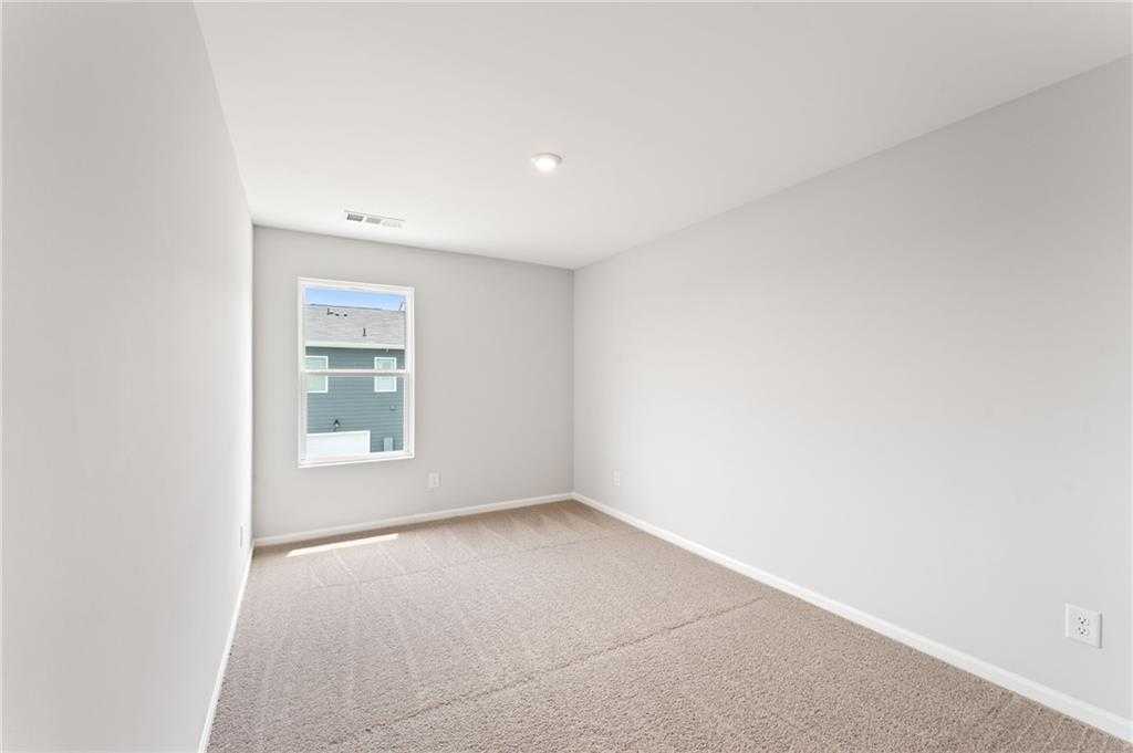 Bright secondary bedroom with gray walls, large window, and beige carpet in Davidson Homes The Monroe A, Emerson, Georgia