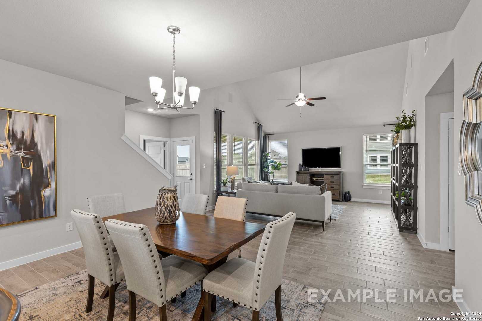 Open-concept living-dining area with wooden table, beige sofa, chandelier, and large windows in Davidson Homes The Collin A, Seguin, Texas