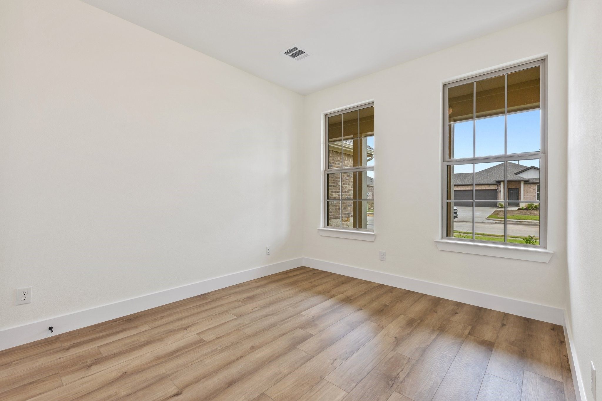 Bright, unfurnished bedroom with wood-look flooring in The Rockford C floor plan at Waverly Estates in Josephine, Texas.