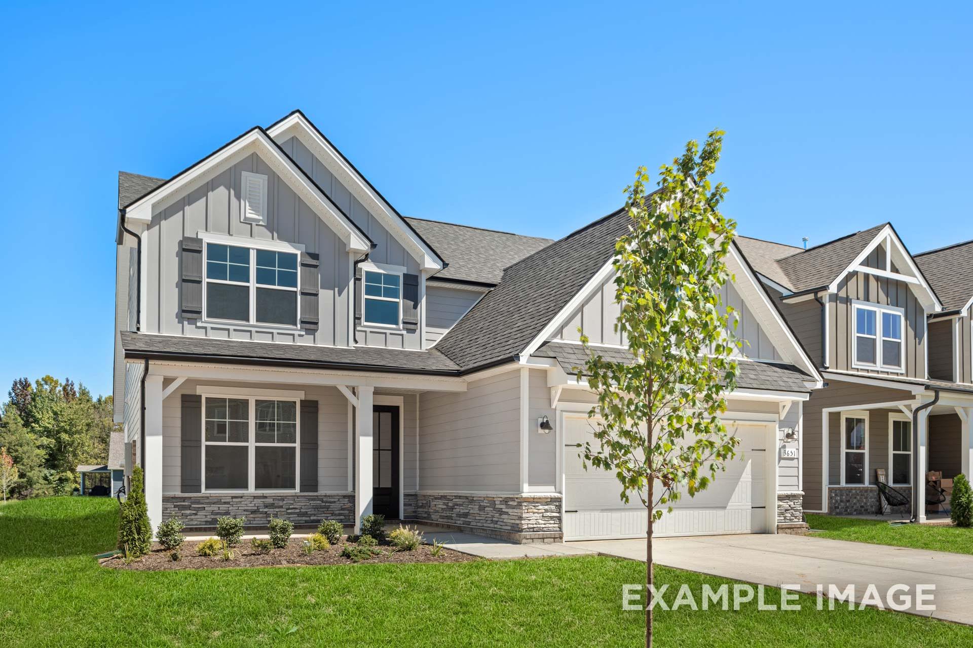 Two-story craftsman exterior of The Ash B home with gray siding, gabled roof, front porch, 2-car garage, and landscaped yard