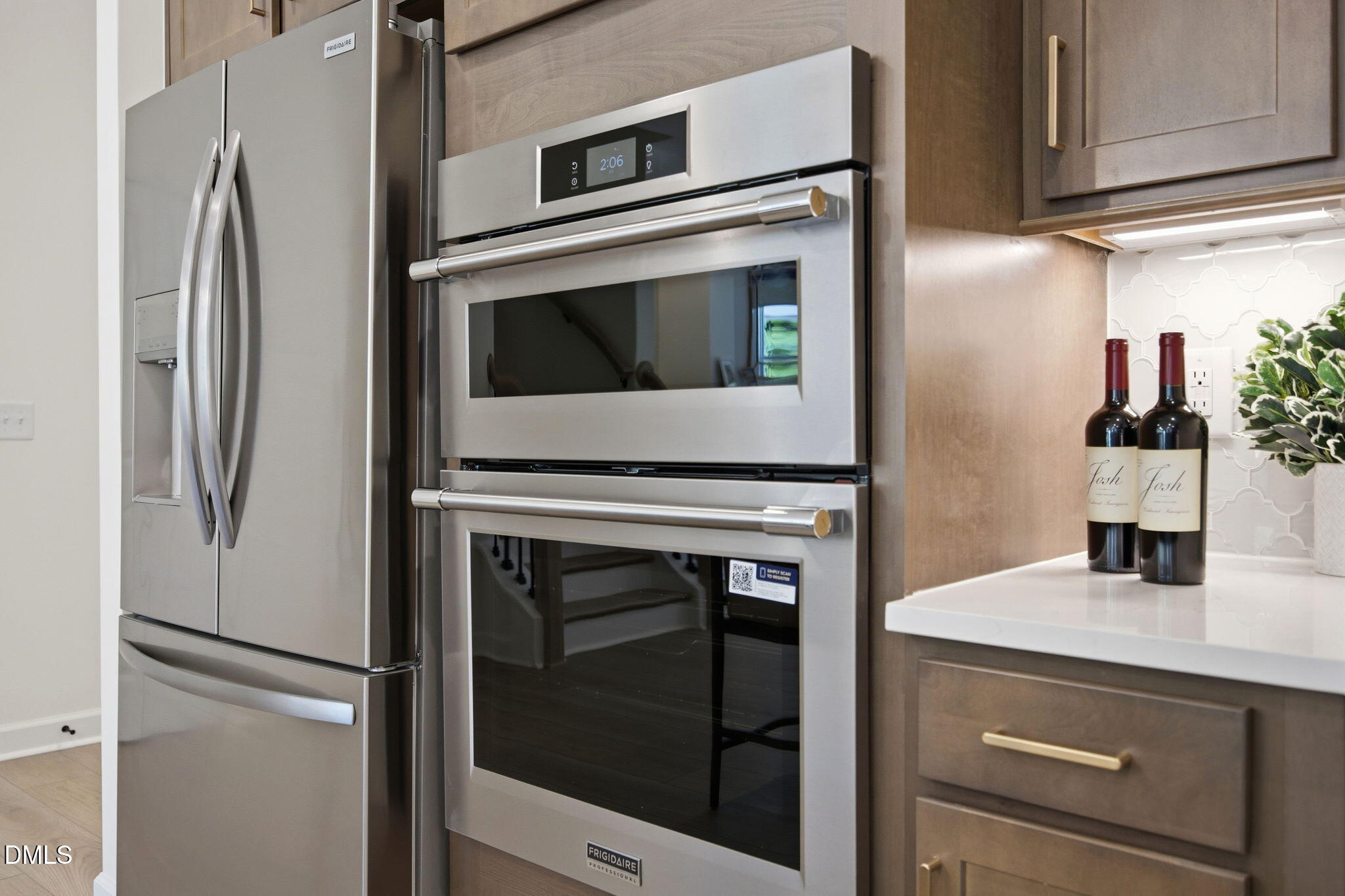 Stainless steel double wall ovens and refrigerator in a modern kitchen at The Ashport M in Wendell Ridge, North Carolina.