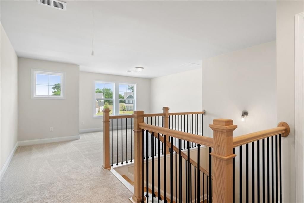 Elegant oak staircase with black balusters in bright upstairs hallway, large windows to greenery, The Willow D at Wehunt Meadows, Hoschton GA