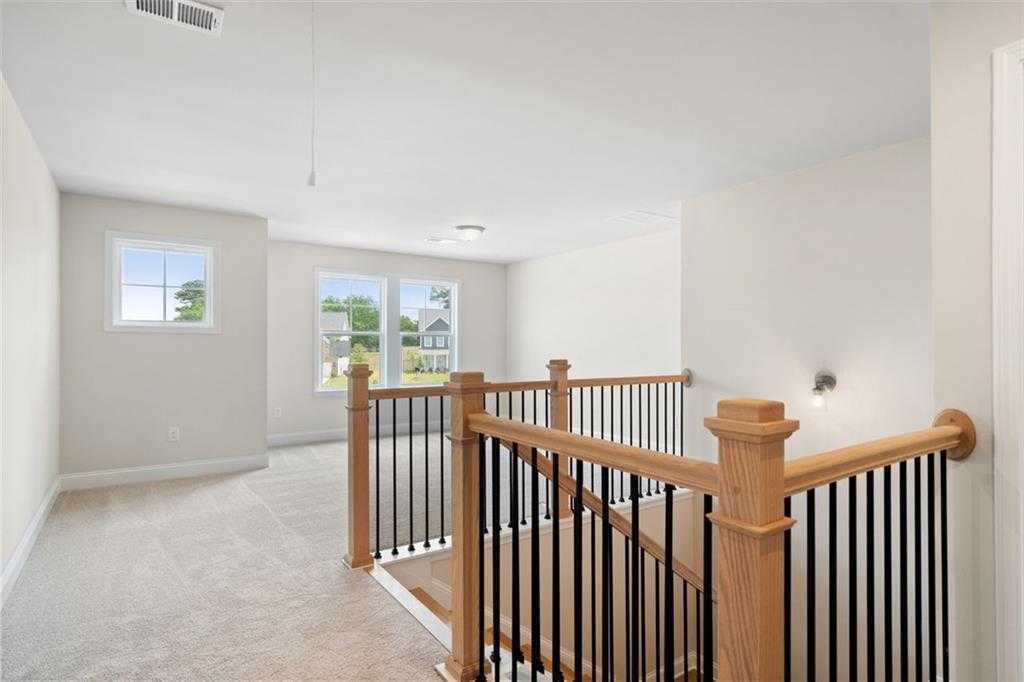Elegant oak staircase with black balusters in bright upstairs hallway, large windows to greenery, The Willow D at Wehunt Meadows, Hoschton GA