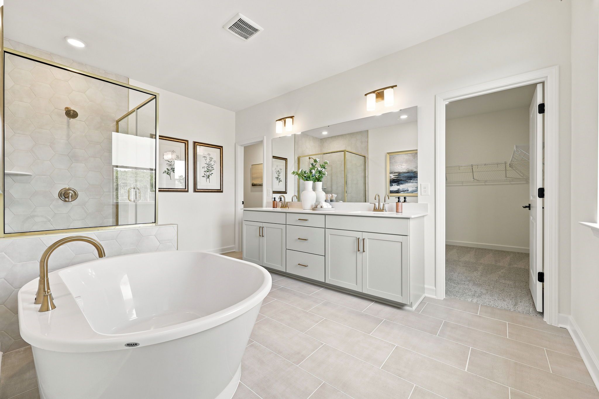Modern primary bathroom at Montrose in Aberdeen, NC by Davidson Homes featuring a soaking tub, dual vanity, and walk-in closet.