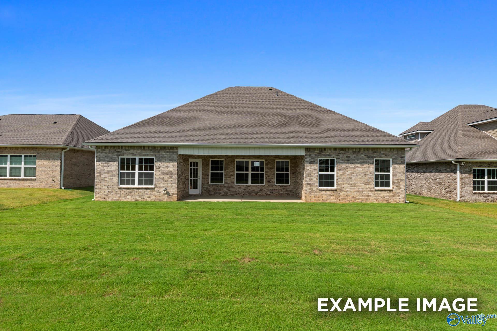 Rear view of single-story brick home with covered patio, large windows, and green yard in The Meadows, Athens, Alabama