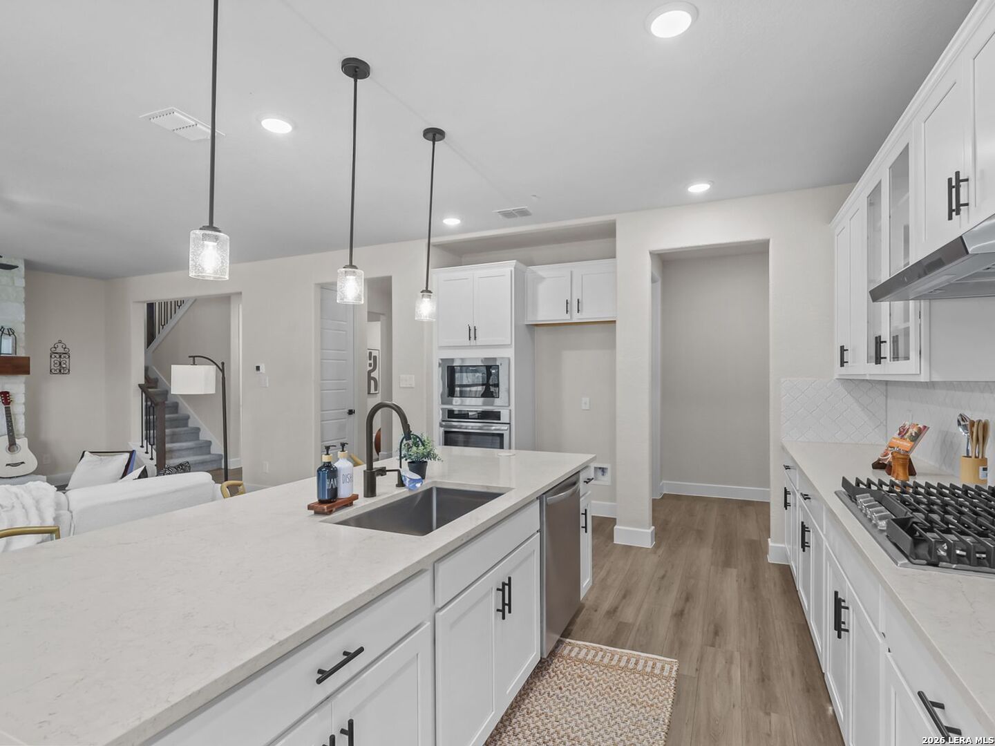 Modern white kitchen with quartz island in The Belmont H floor plan at Potranco Oaks, Castroville, Texas.